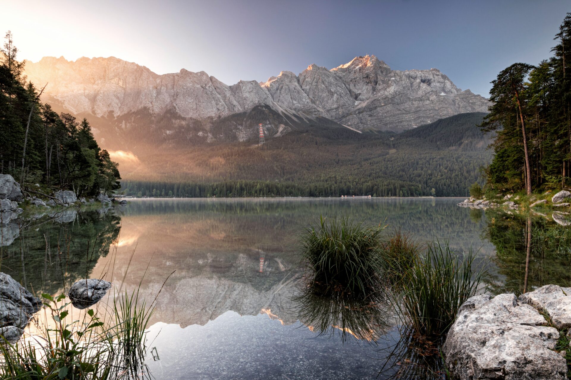 Peaceful view of Lake Eibsee with calm, clear water, surrounding forest, and the Zugspitze mountain 