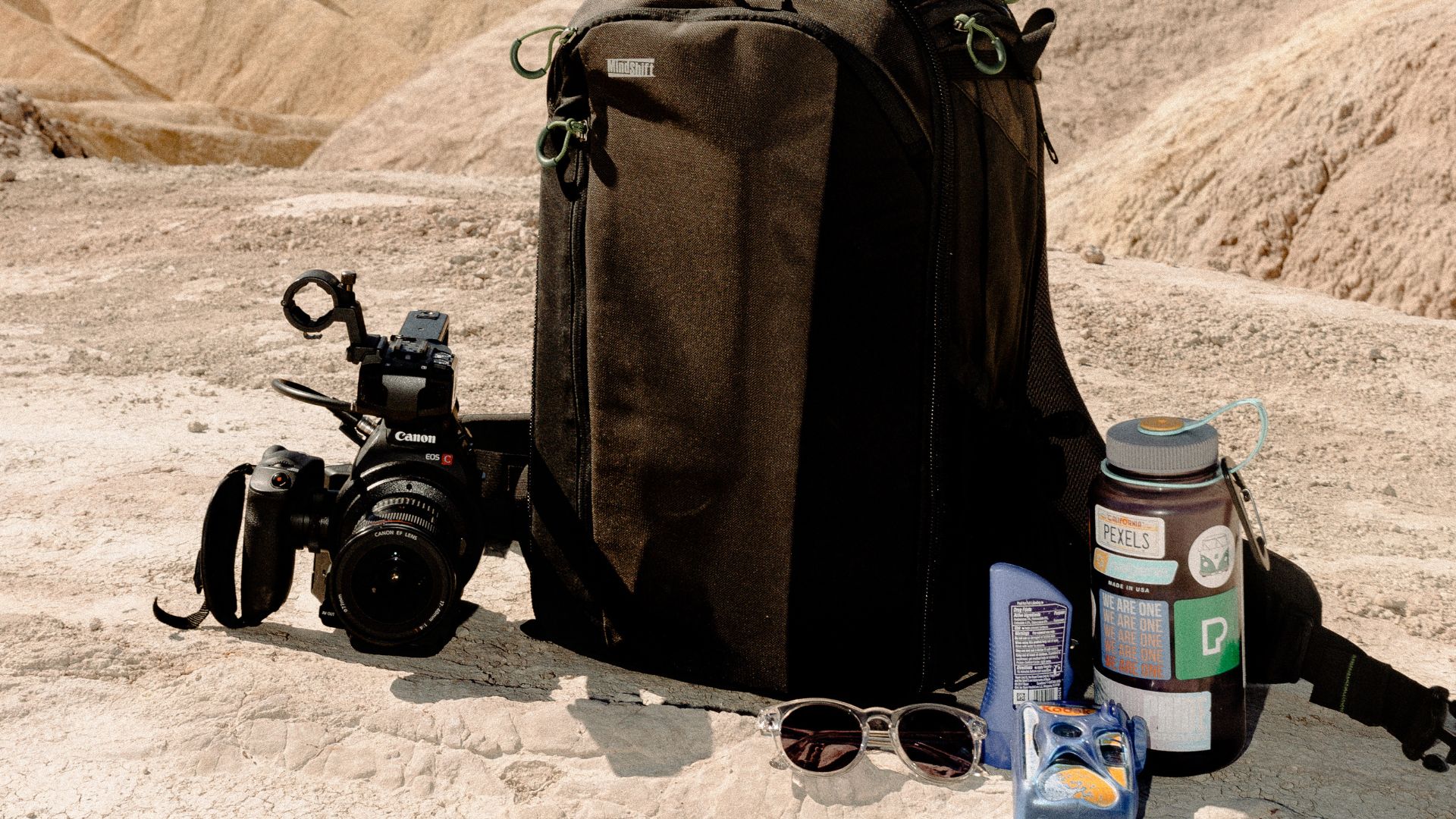 A bag, camera, water bottle, sunscreen, 