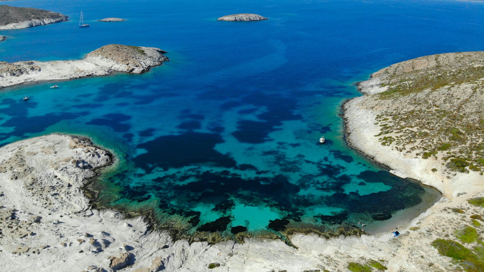 Aerial view of Faneromeni Beach in Antiparos, Greece, showcasing clear turquoise waters and unique rock formations.