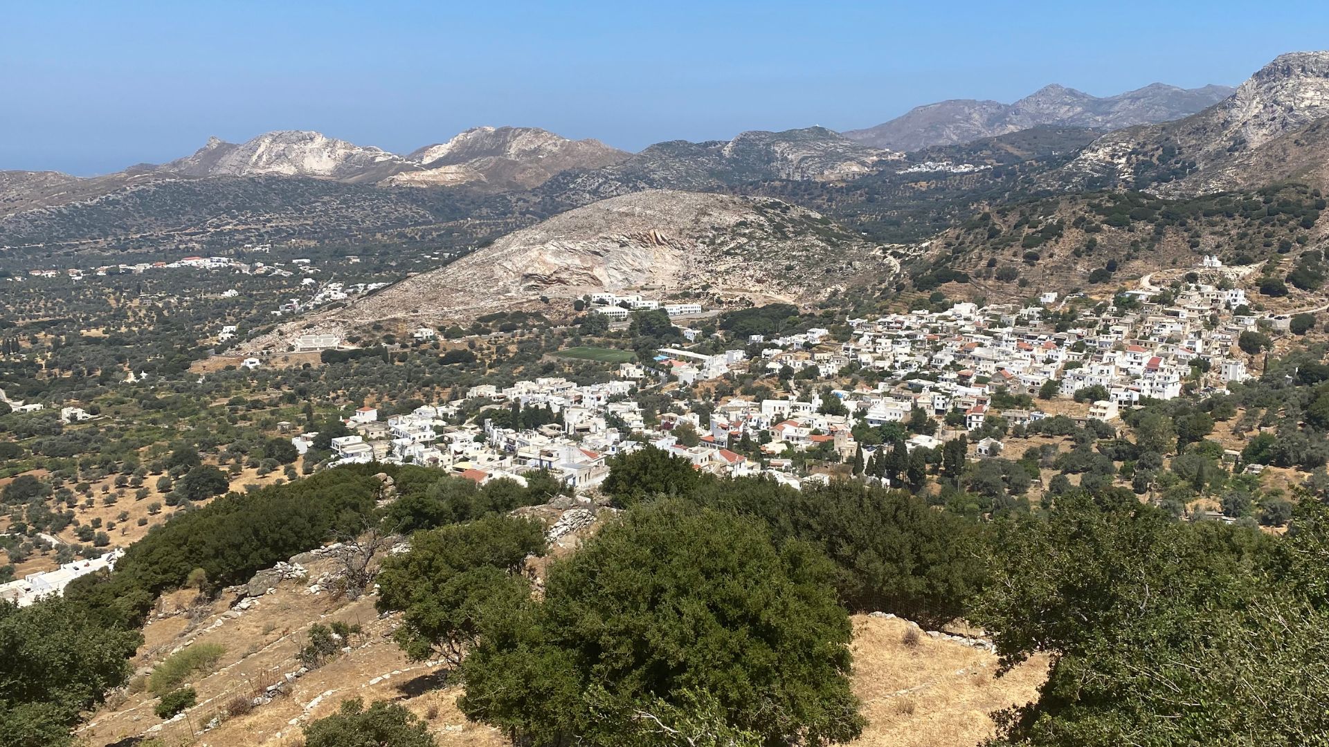 An aerial view of the village of Filoti in Greece, nestled in a mountainous landscape.