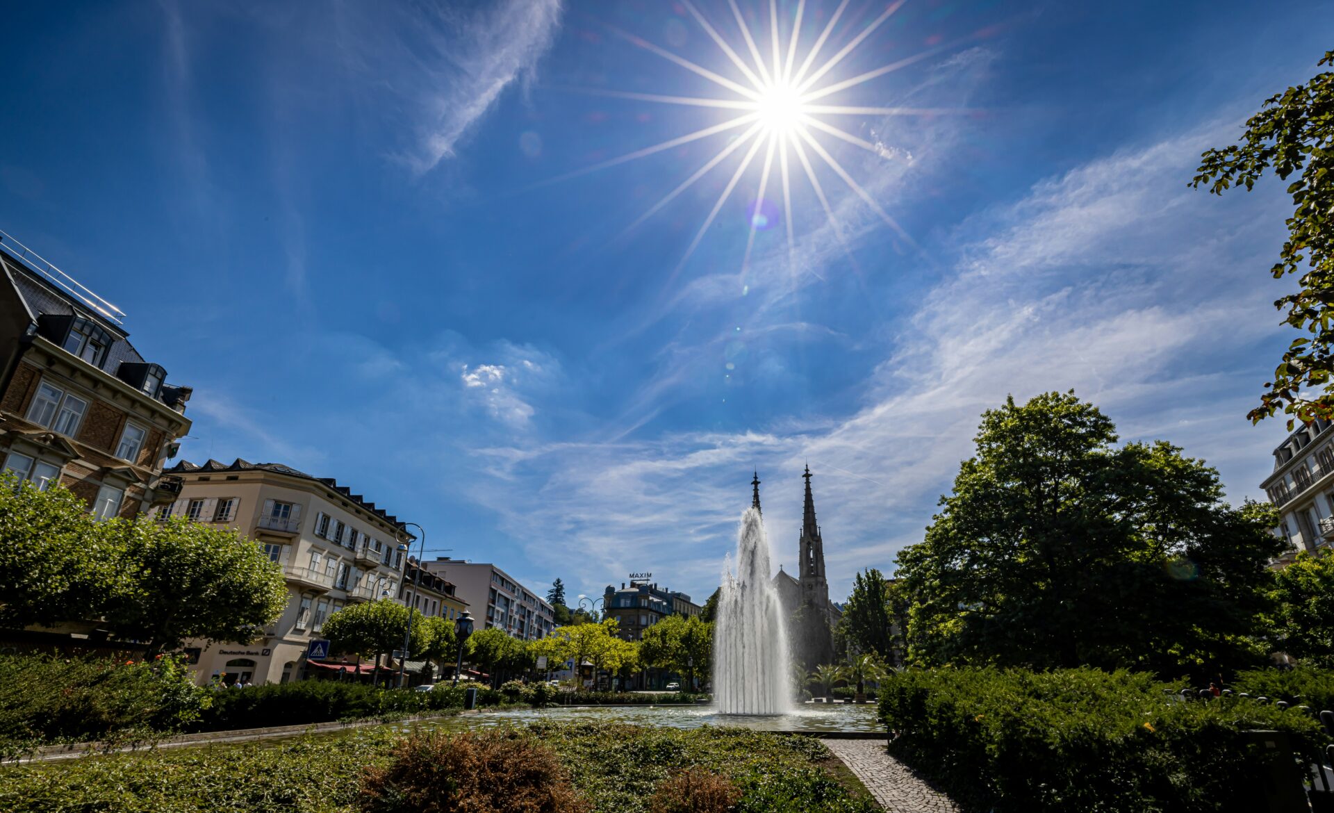 Fountain in a well-manicured garden in Baden-Baden, glistening under a clear blue summer sky