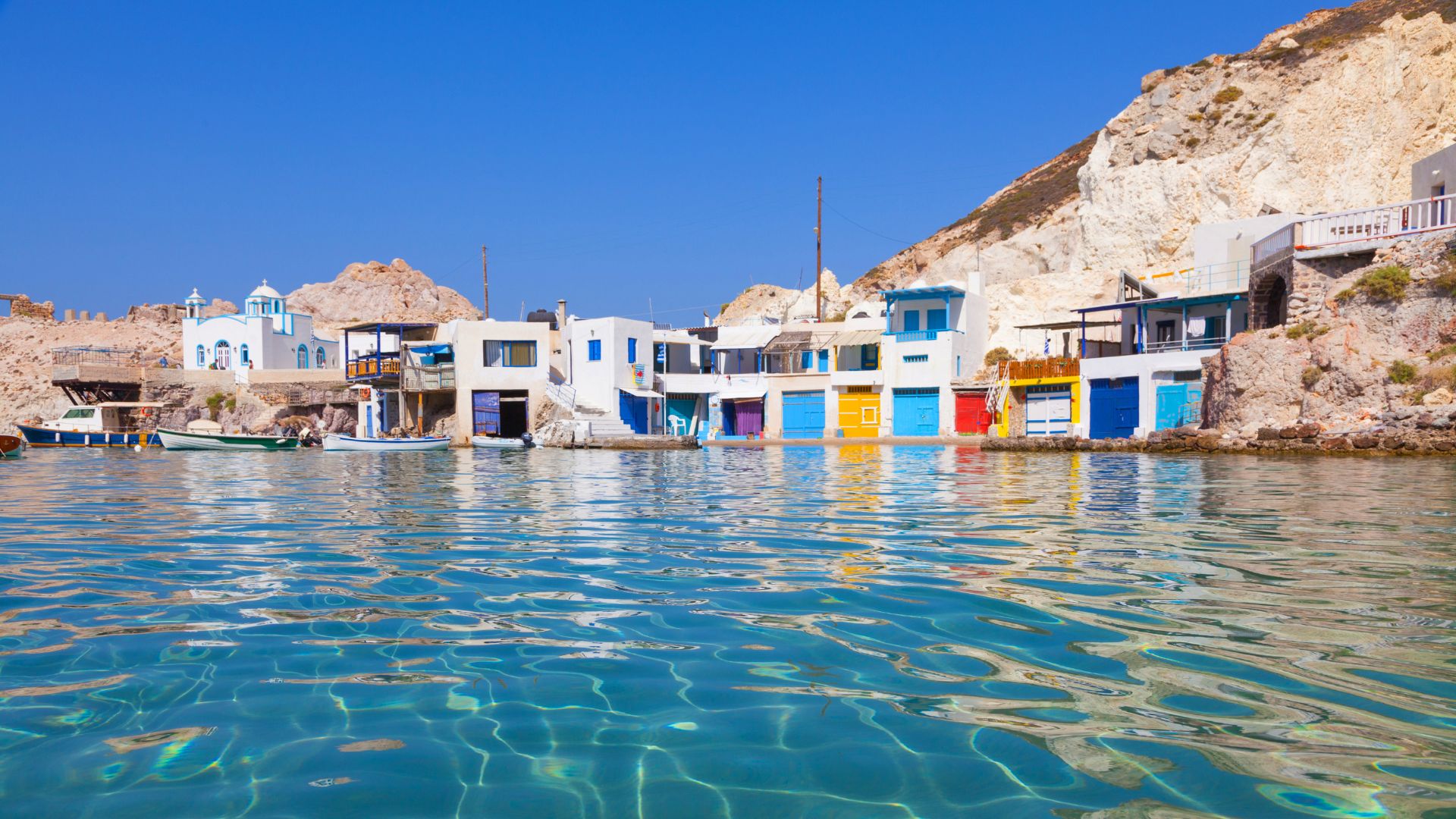 Fyropotamos village in Milos, Greece featuring colorful boat garages and turquoise waters.