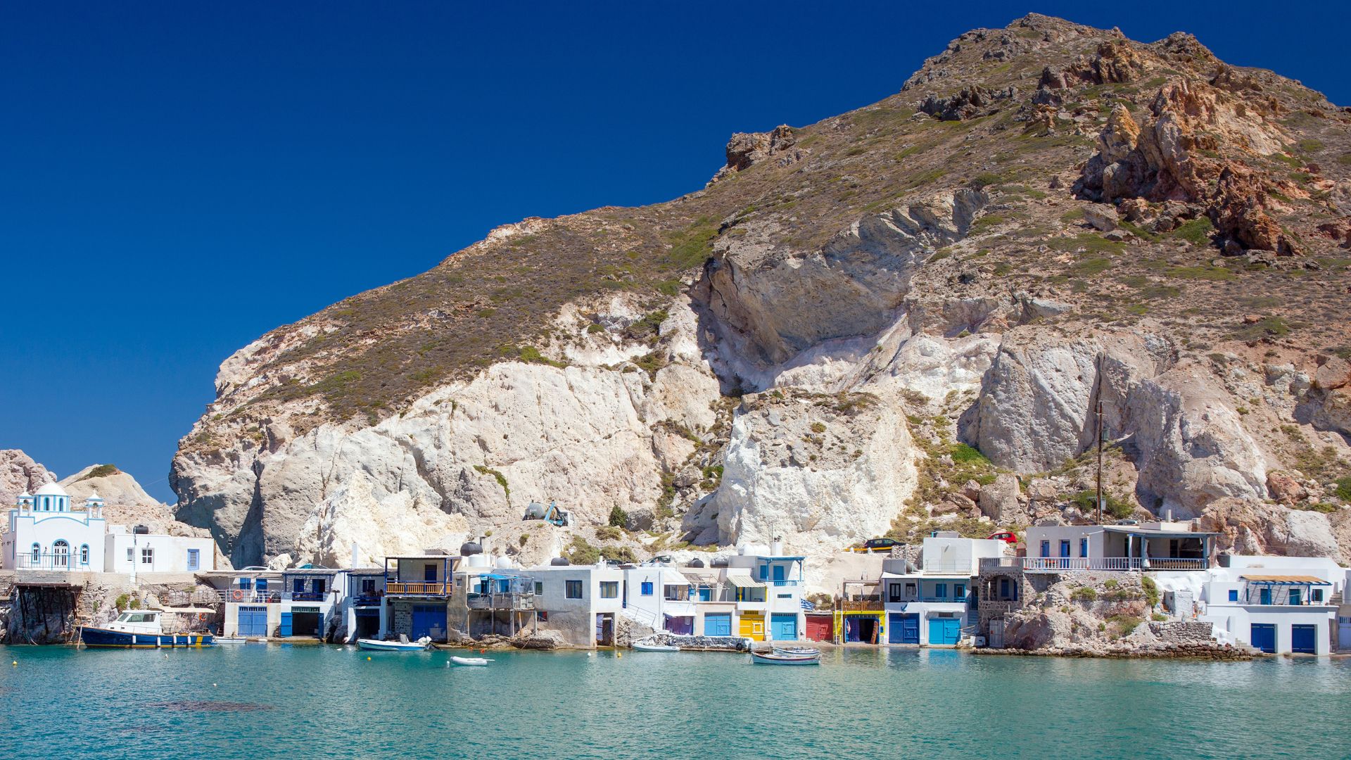 Fyropotamos village in Milos, Greece featuring colorful boat garages and turquoise waters.