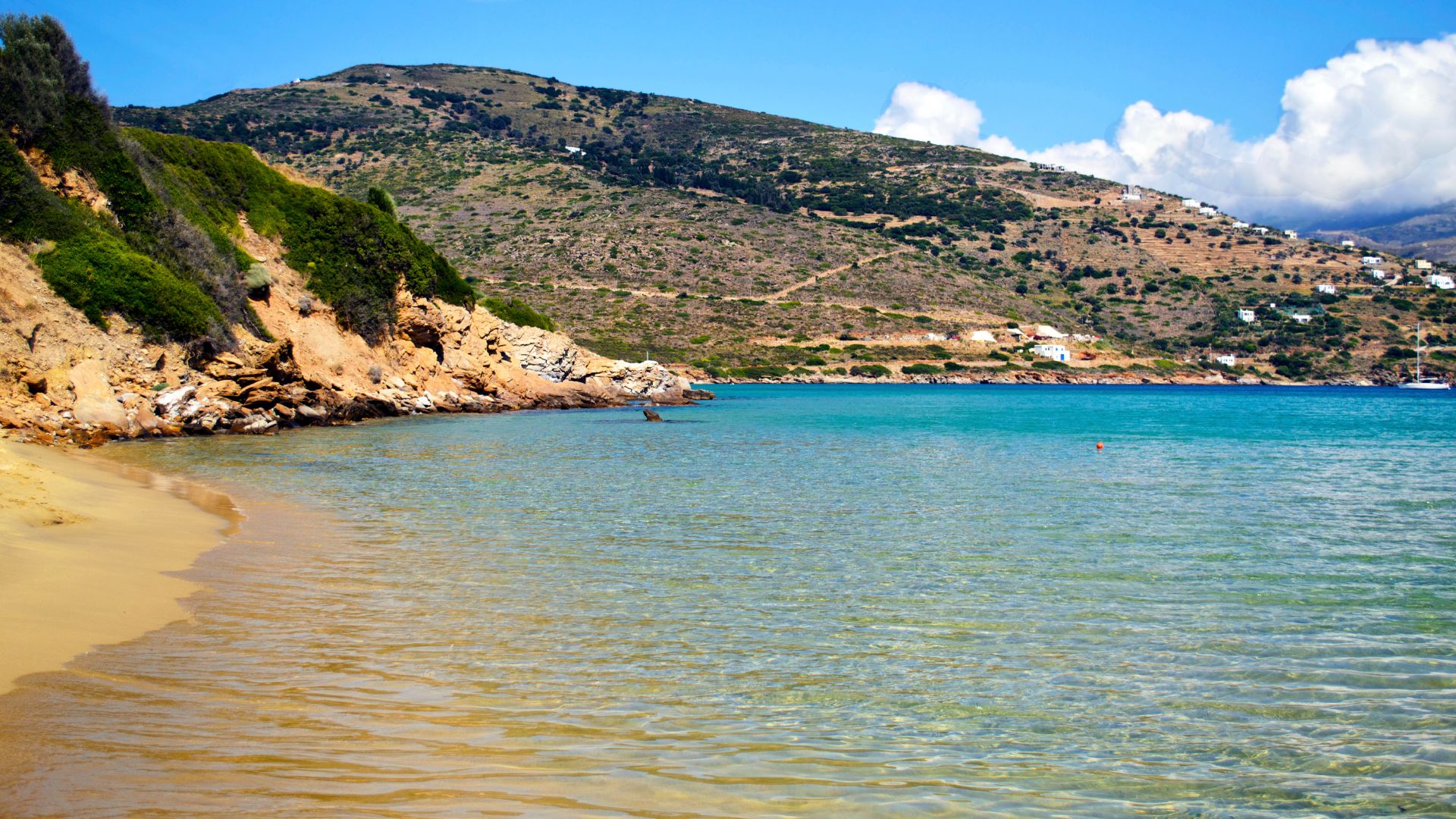 Sccenic view of Golden Beach (Chrissi Akti) in Paros, Greece featuring its mountain, white sand beach, and clear waters.