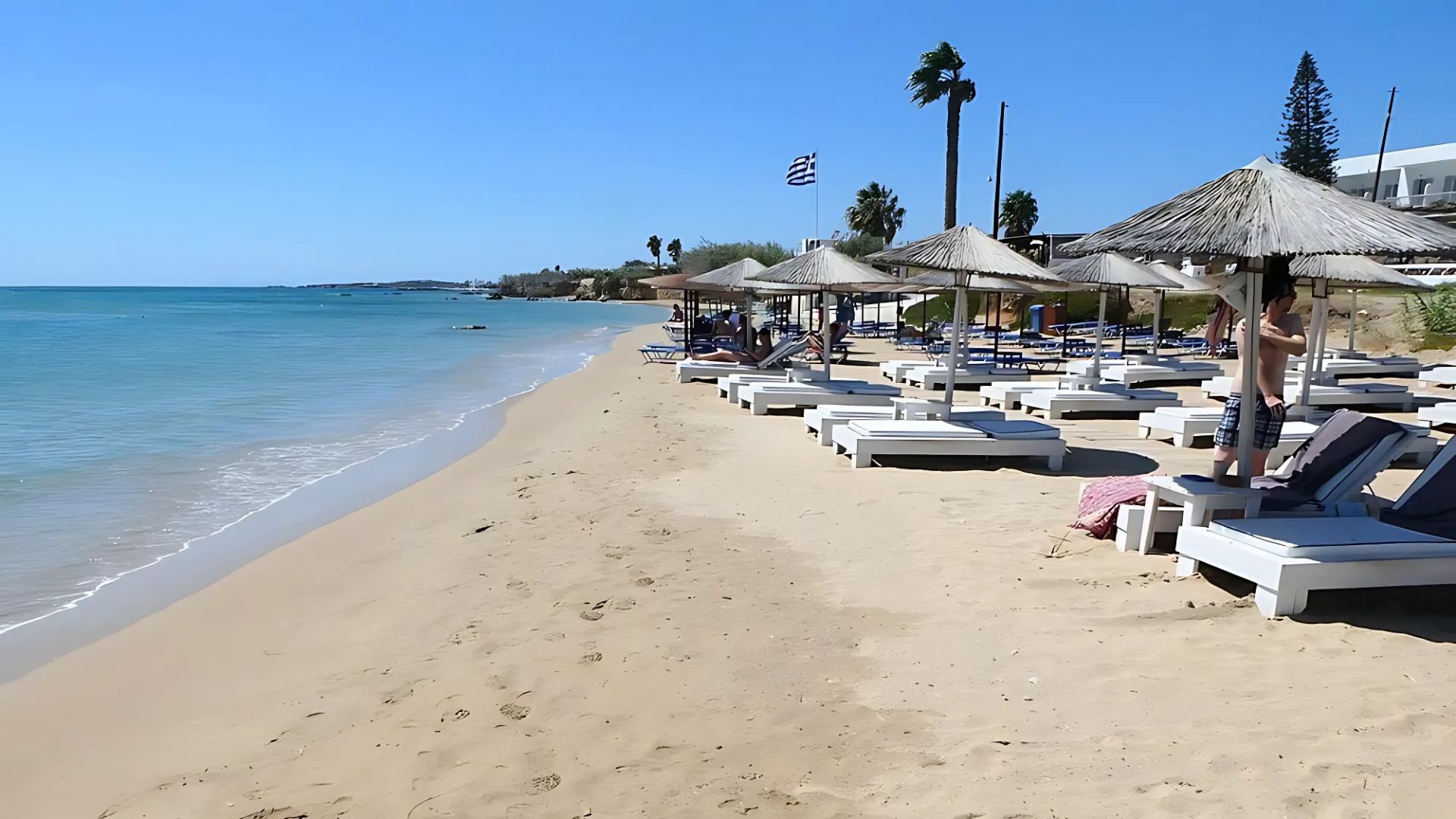 Golden Beach in Paros, Greece, with sunbeds and umbrellas on a sandy shore.