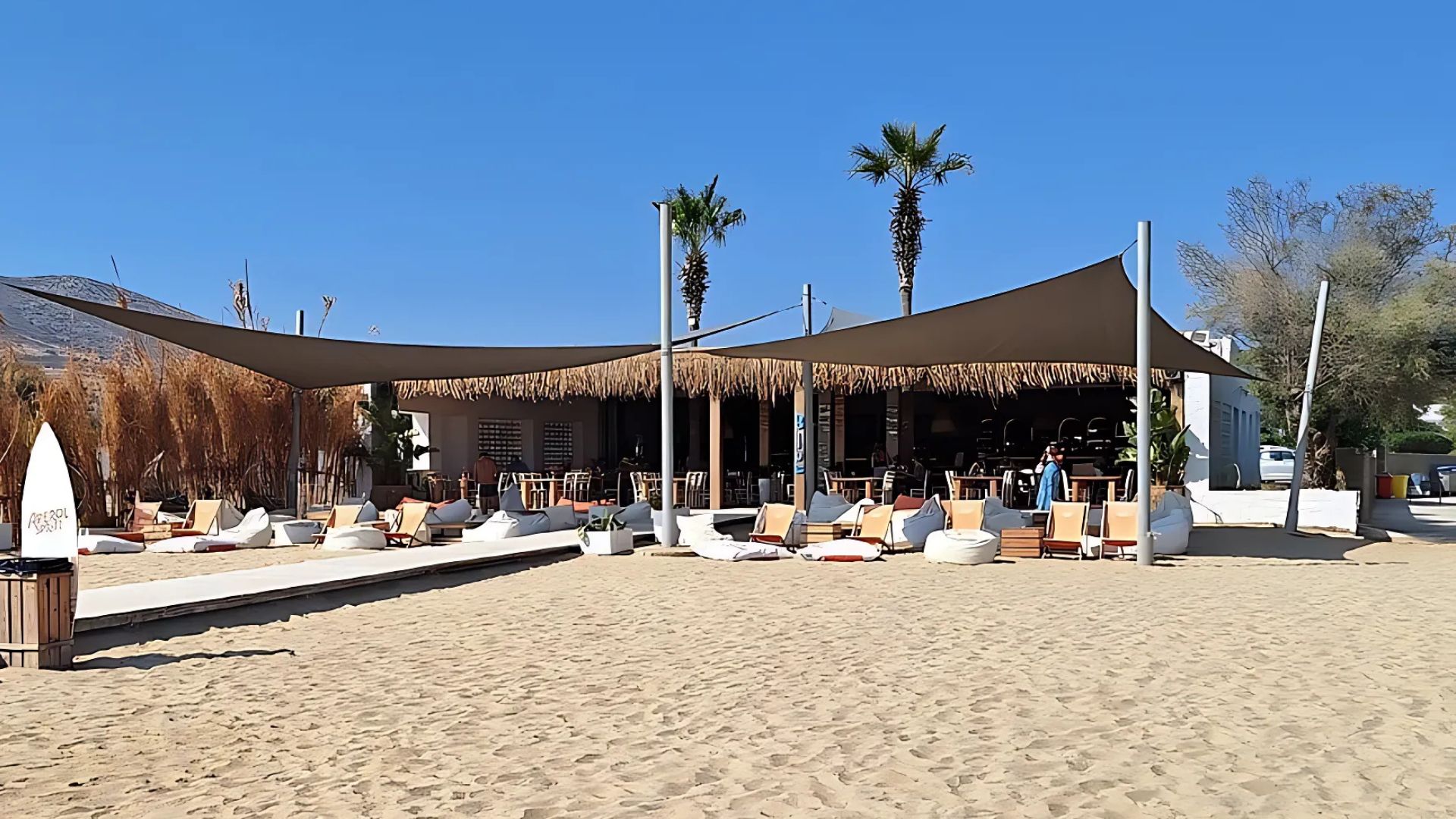 Golden Beach in Paros, Greece, a cafe with sunbeds and umbrellas on a sandy shore.
