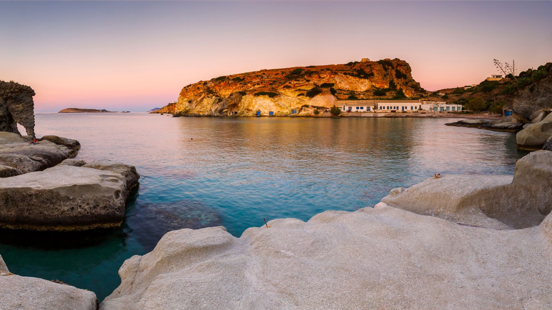 Boat houses in fishing village of Goupa on Kimolos island in Greece at sunset.