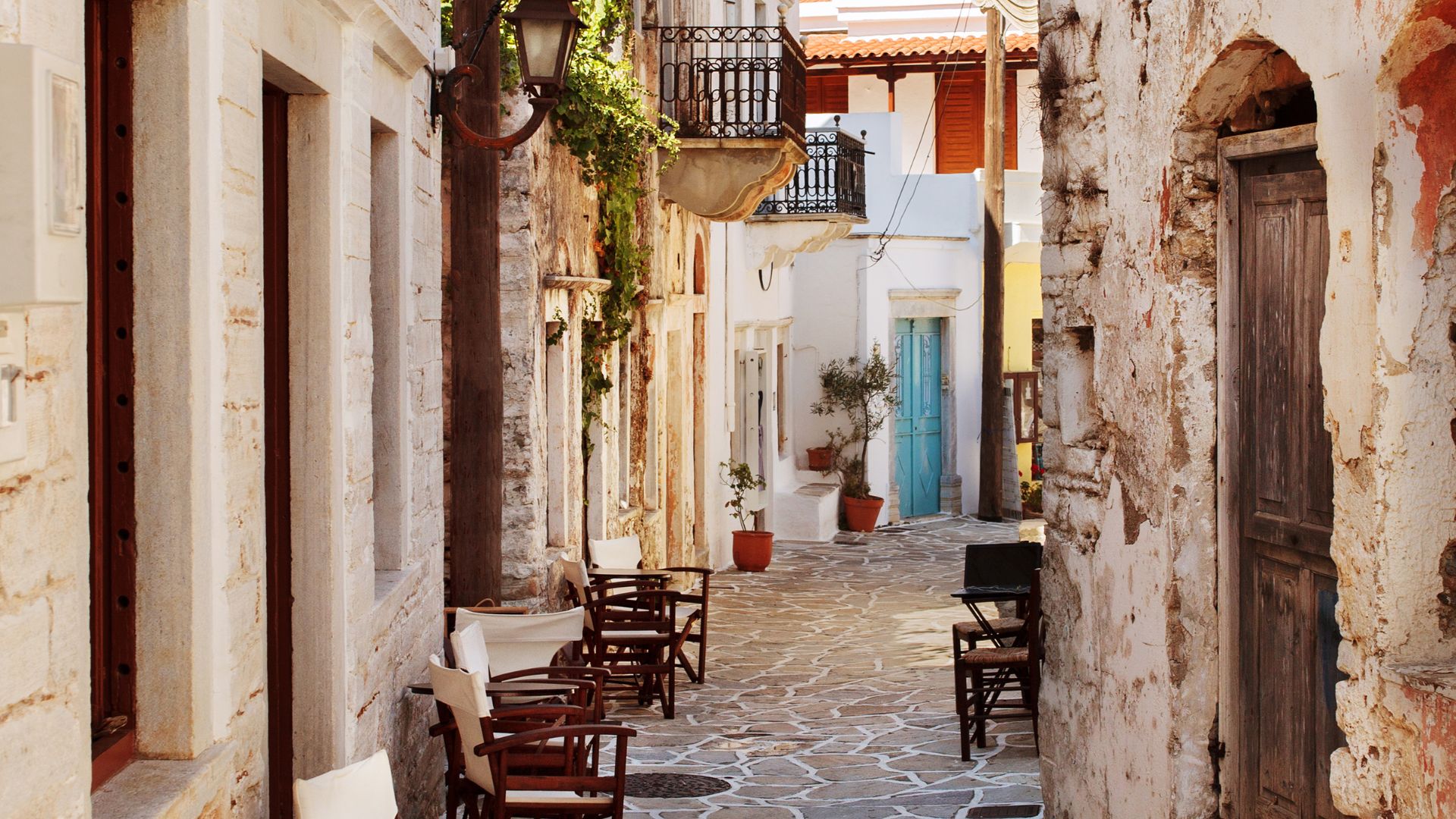 A narrow, stone-paved street lined with traditional buildings in Halki village, Naxos, Greece.
