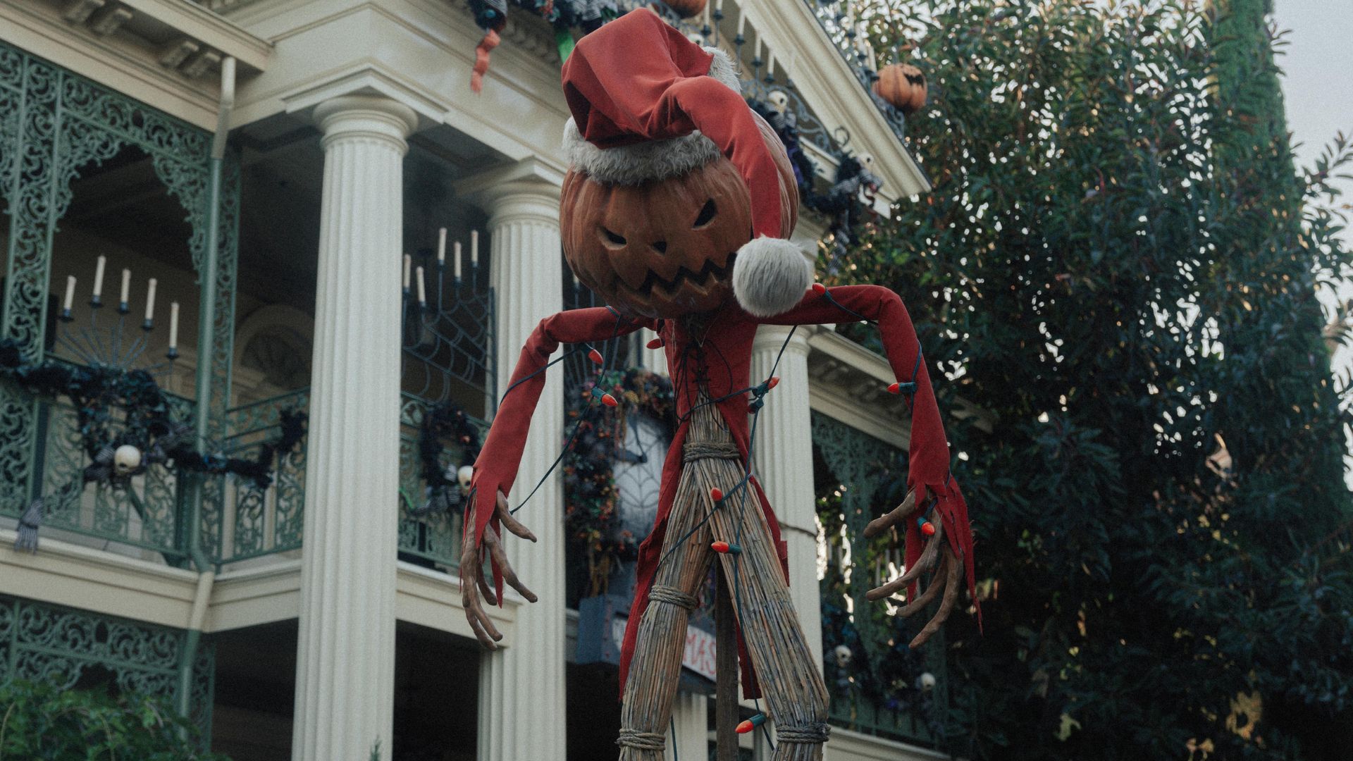 Haunted Mansion Holiday attraction at Disneyland Park in Anaheim, featuring the iconic mansion decorated with pumpkins and a large Pumpkin King scarecrow from The Nightmare Before Christmas