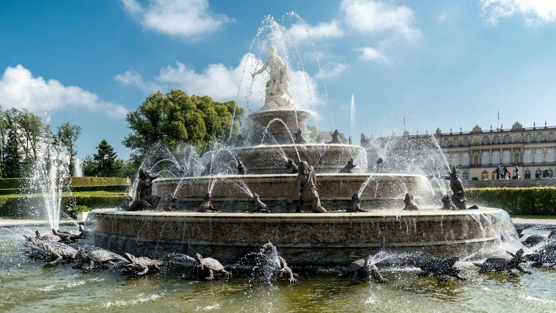 Grand fountain in front of Herrenchiemsee Palace with ornate sculptures and water jets