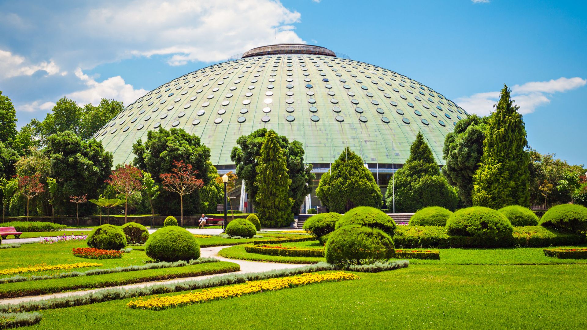 Jardins do Palácio de Cristal in Porto, Portugal, featuring the Rosa Mota Pavilion and beautifully landscaped gardens with vibrant flowers and lush greenery. The gardens offer scenic views of the city and the Douro River.