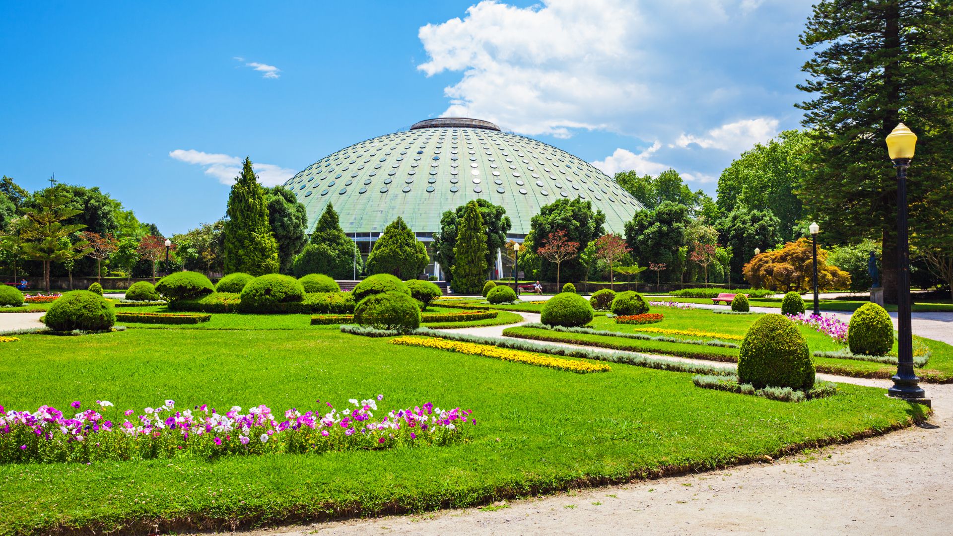 Jardins do Palácio de Cristal in Porto, Portugal, featuring the Rosa Mota Pavilion and beautifully landscaped gardens with vibrant flowers and lush greenery. The gardens offer scenic views of the city and the Douro River.