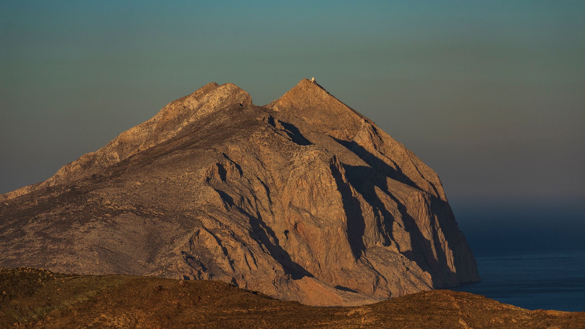 Kalamos Rock Anafi Greece with Monastery of Panagia Kalamiotissa at sunset