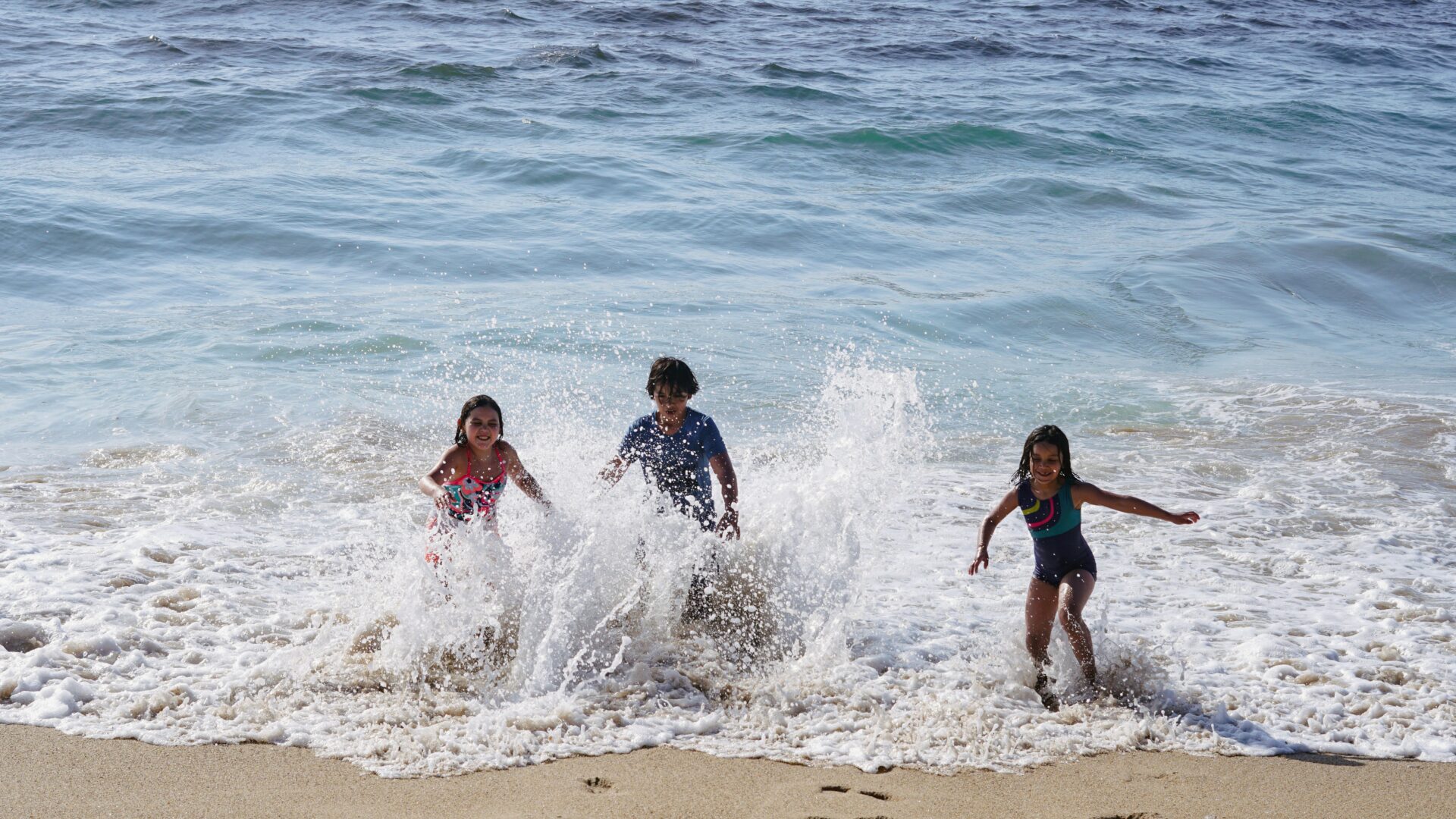 Kids playing at the beach shoreline with seawaves