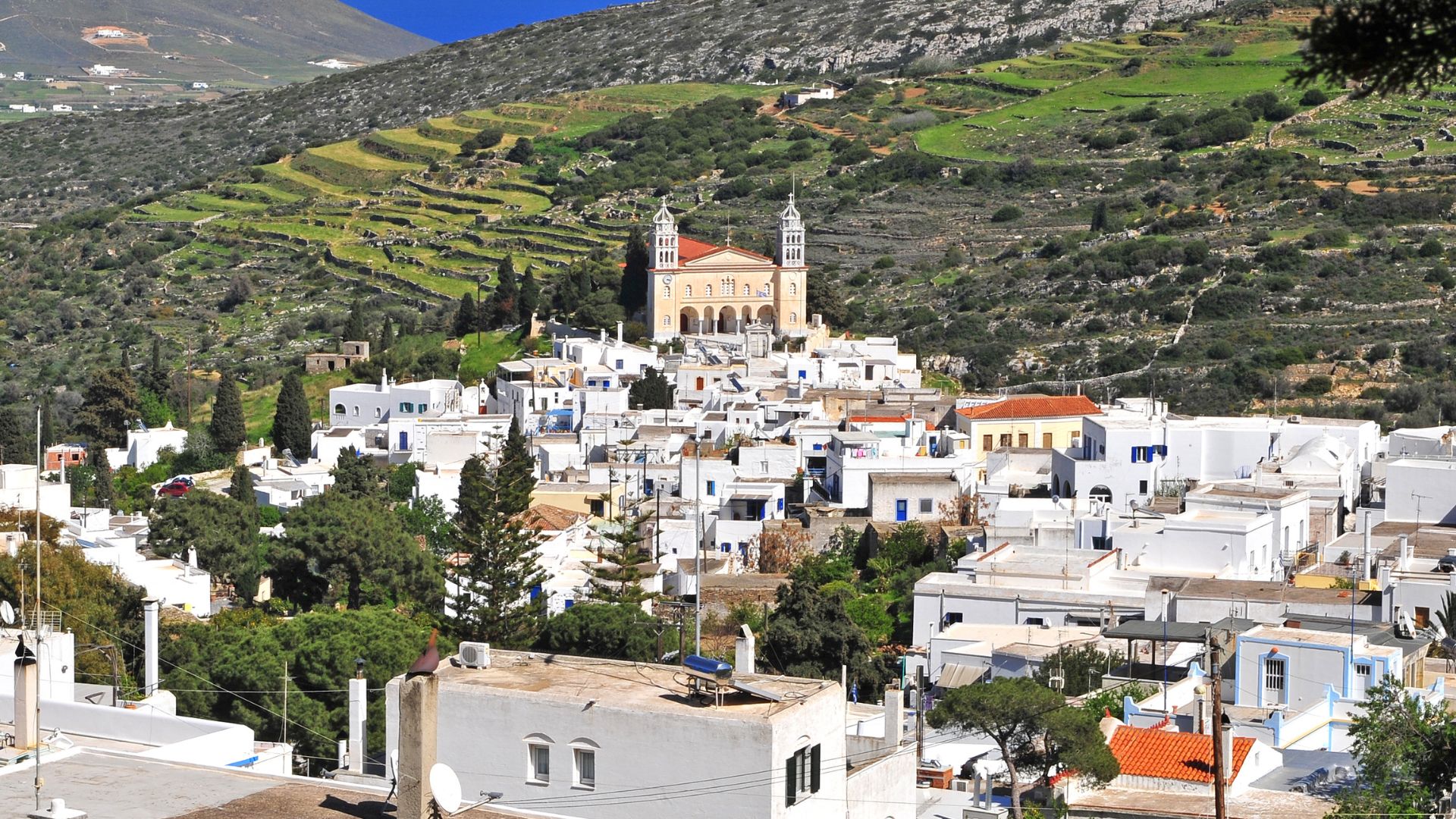A picturesque village on a hillside in Paros, Greece, with white buildings and a church.