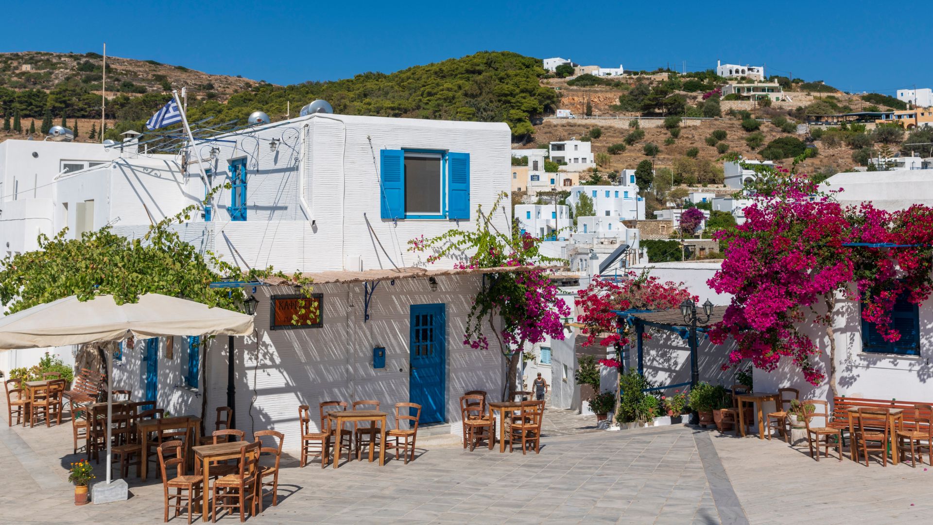 A picturesque village scene in Lefkes, Paros, with white-washed buildings, blue accents, and vibrant bougainvillea.