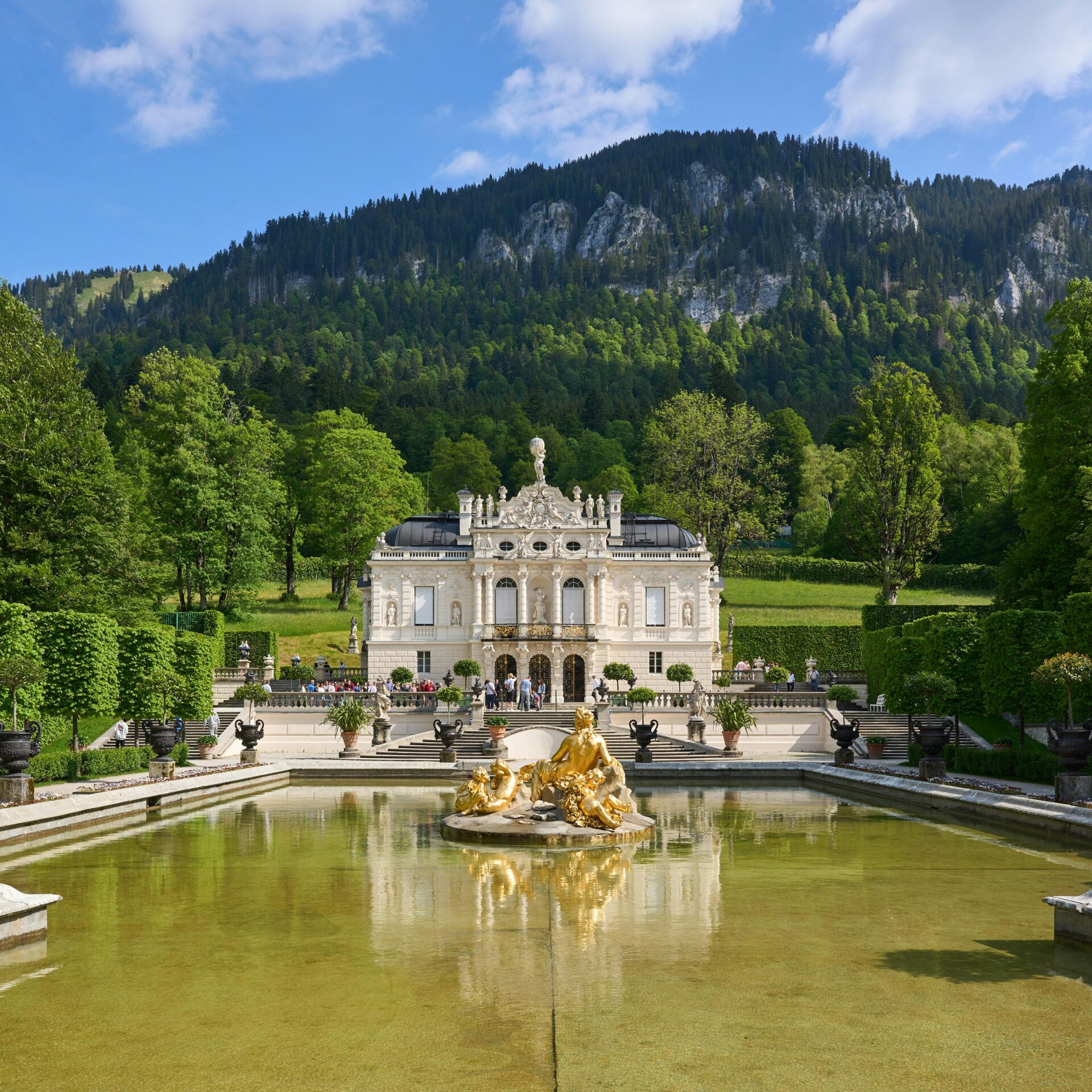 Baroque-style Linderhof Palace surrounded by symmetrical parterre and forested hills