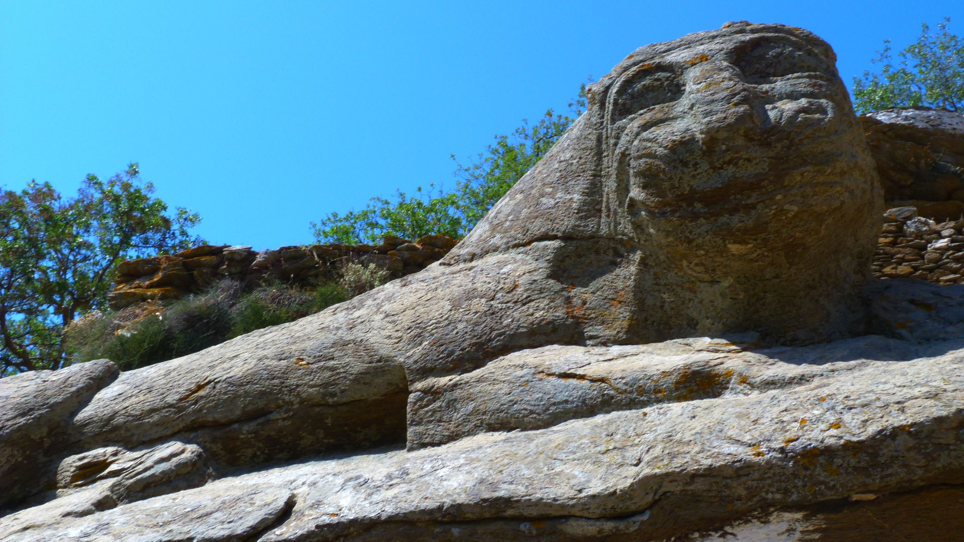 Ancient stone lion sculpture, Lion of Kea, on a Greek island, symbolizing protection and history.