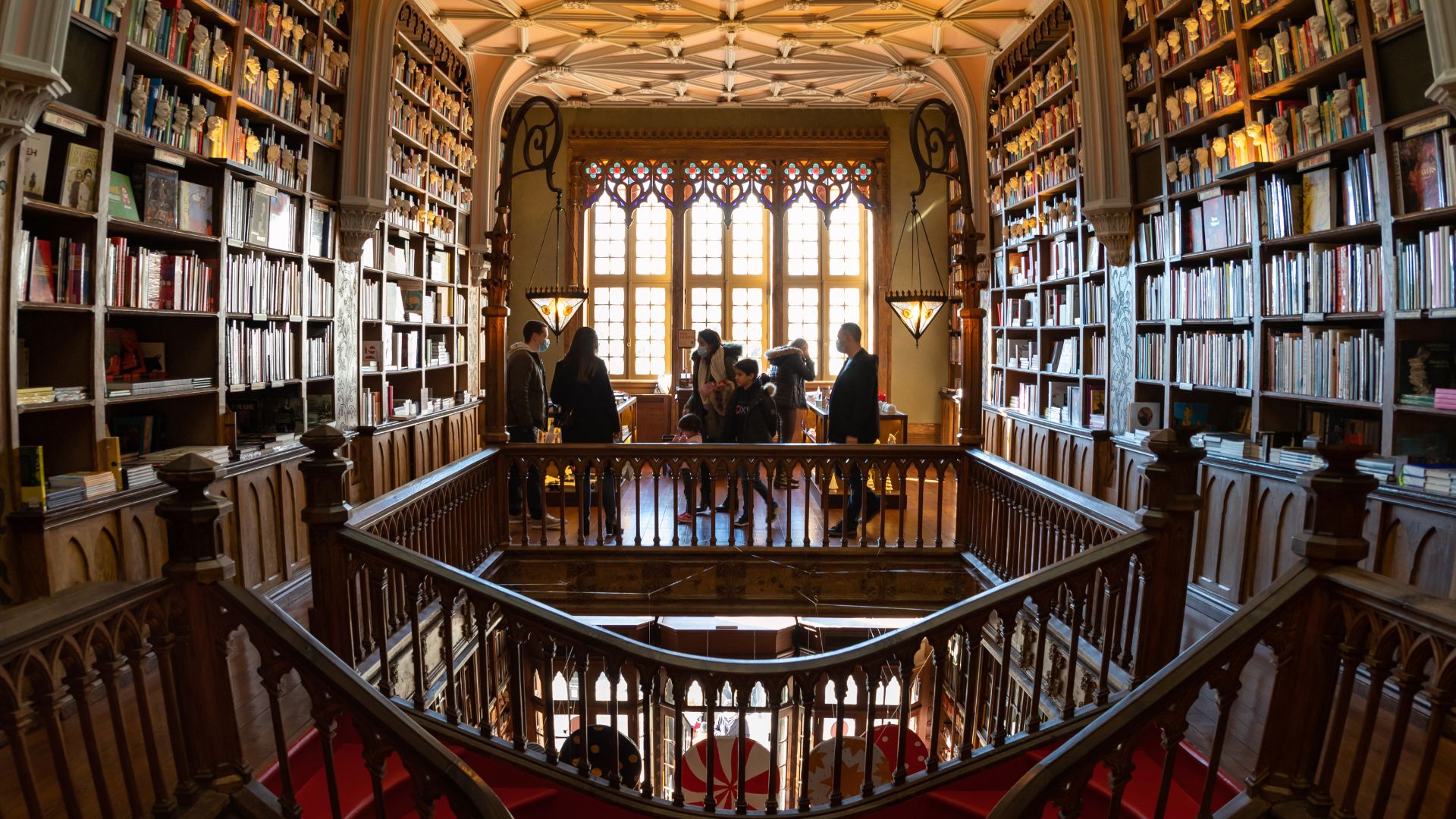 Interior of Livraria Lello, a historic bookstore in Porto, Portugal, featuring its iconic wooden staircase and stained glass windows.