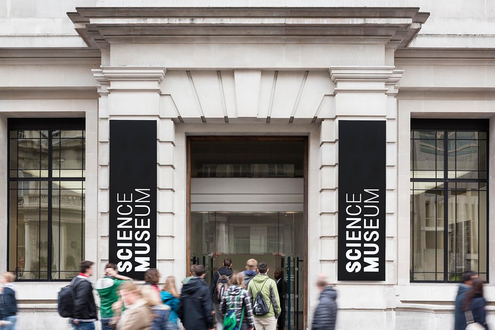 Exterior view of the London Science Museum with people gathered outside near the entrance.