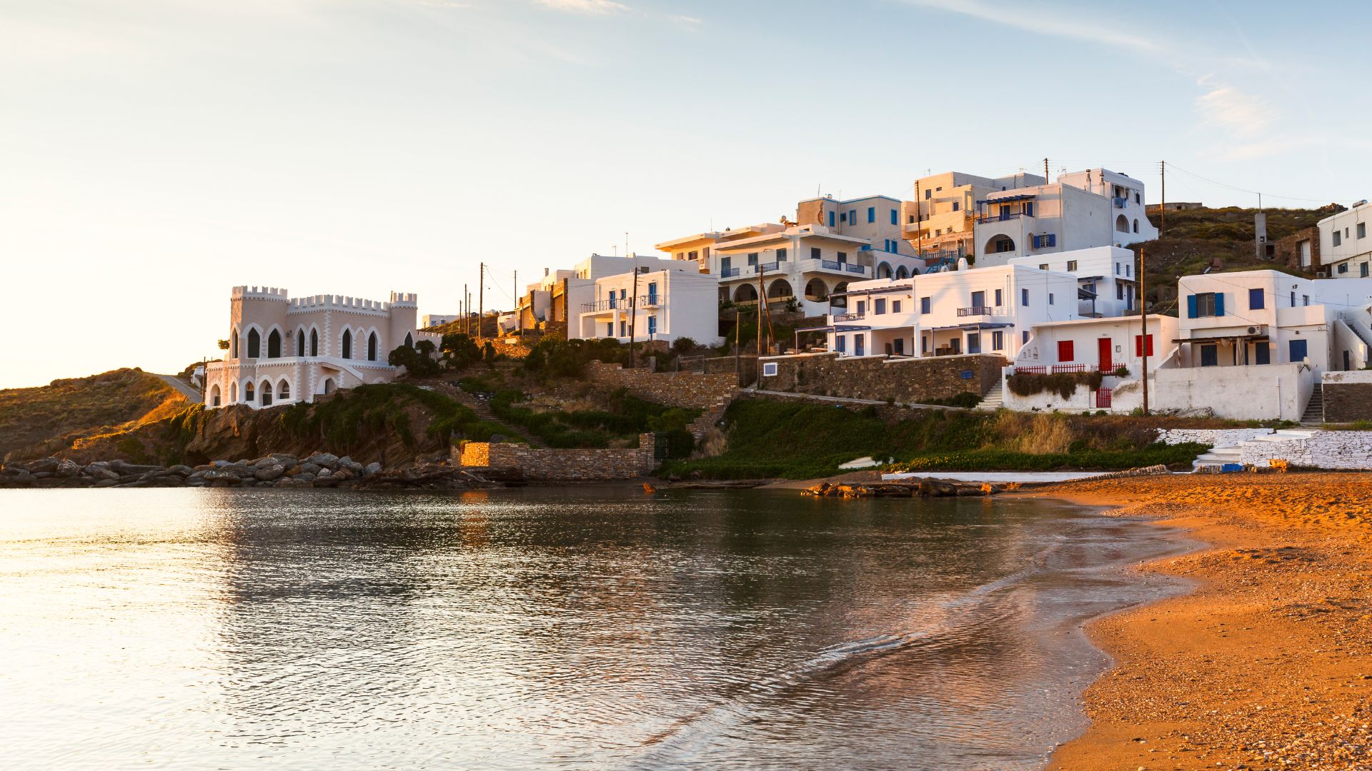 Loutra village on Kythnos Island, Greece, featuring whitewashed buildings and calm bay waters at sunrise.