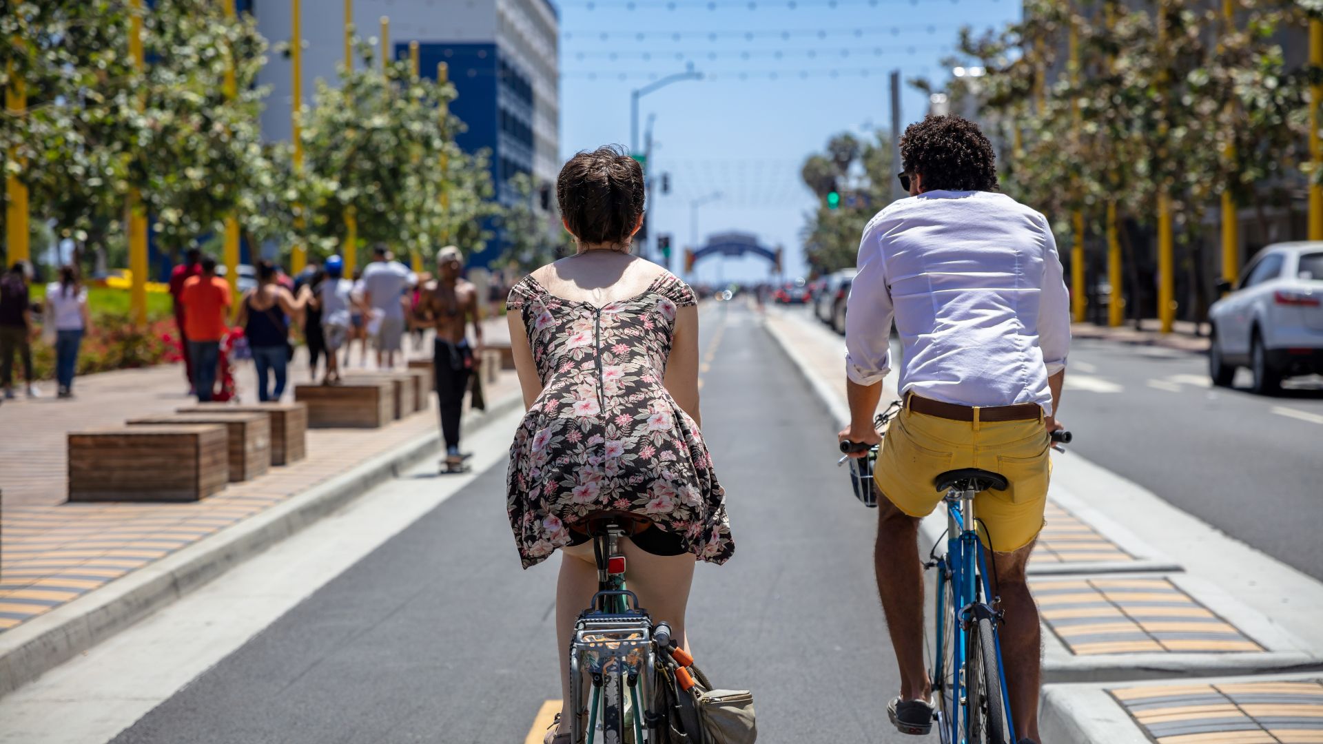 The image depicts a man and a woman riding bicycles side-by-side on a paved path, which aligns with the description of the Marvin Braude Bike Trail as a paved bicycle path. 