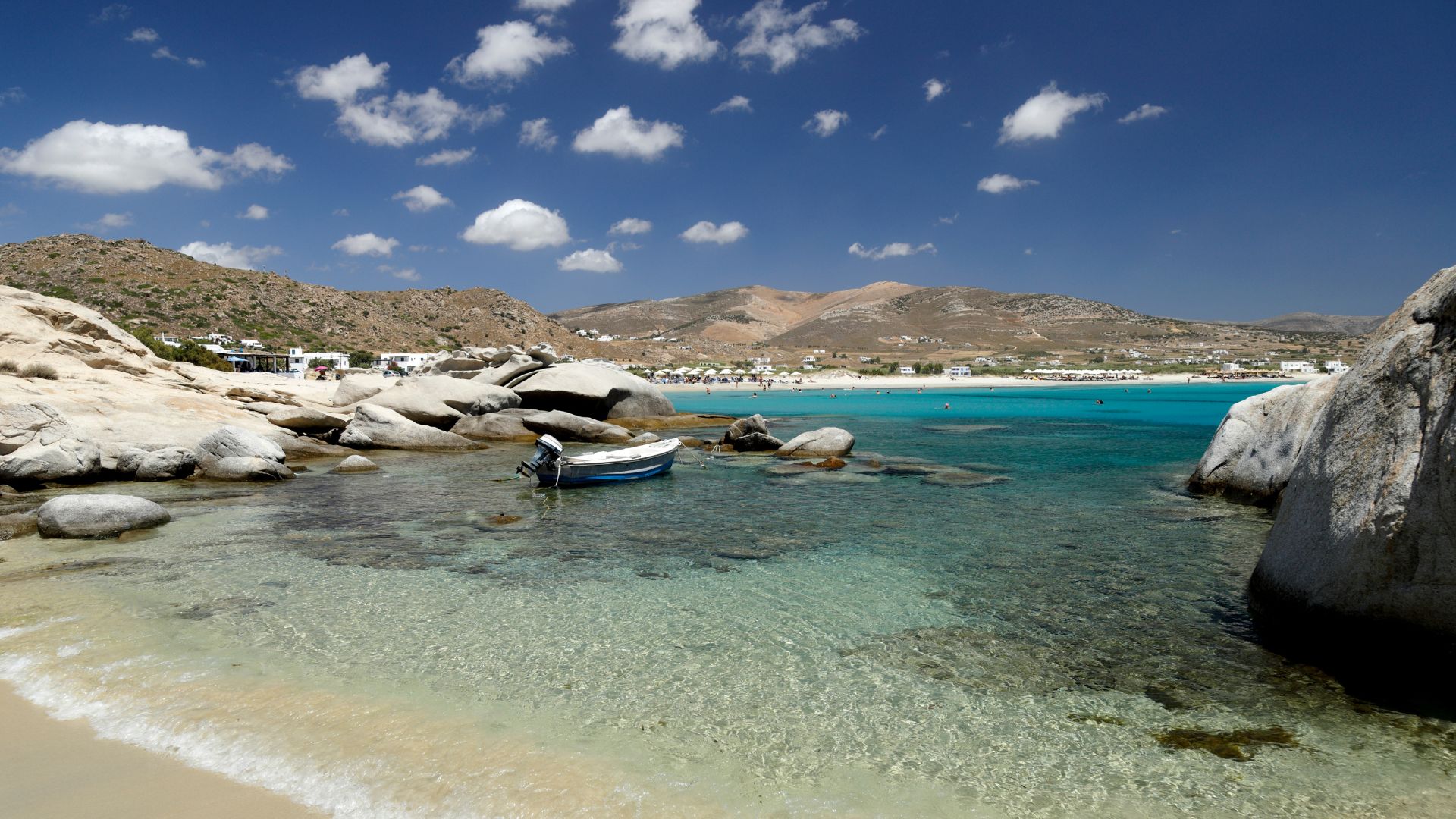 A scenic view of Mikri Vigla beach in Naxos, Greece, with turquoise waters and rocky outcrops.