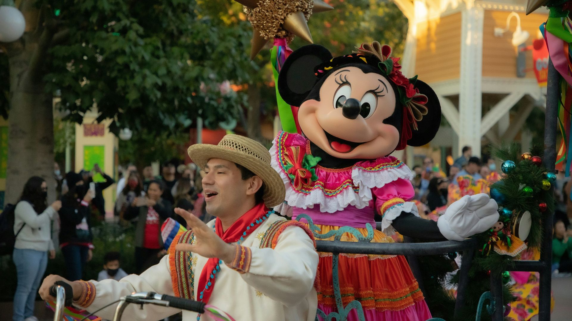 Minnie Mouse on a colorful parade float during the Disney ¡Viva Navidad! Street Party at Disney California Adventure Park, featuring festive holiday decorations and performers in traditional attire.