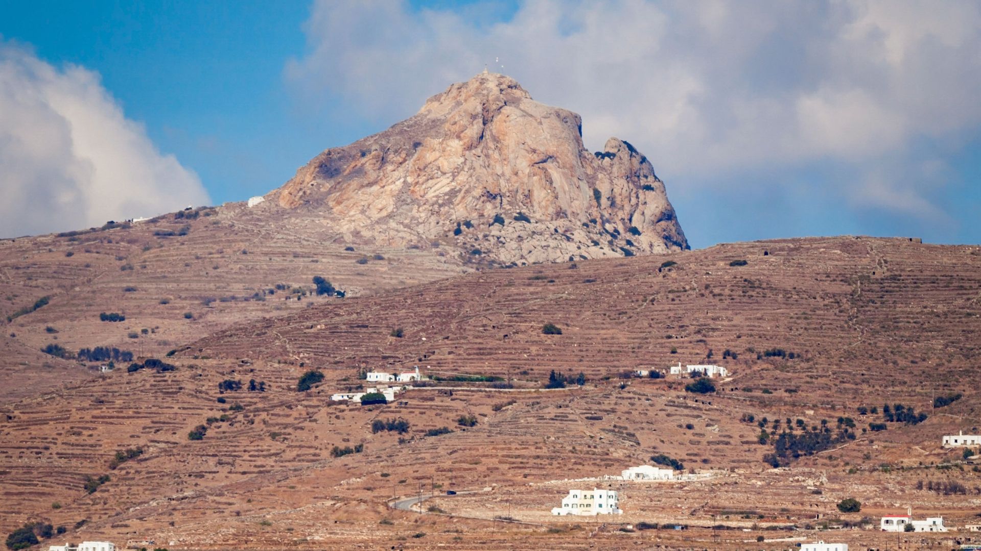 Mount Exomvourgo in Tinos, Greece, a rocky hill with a historical castle ruin on top.