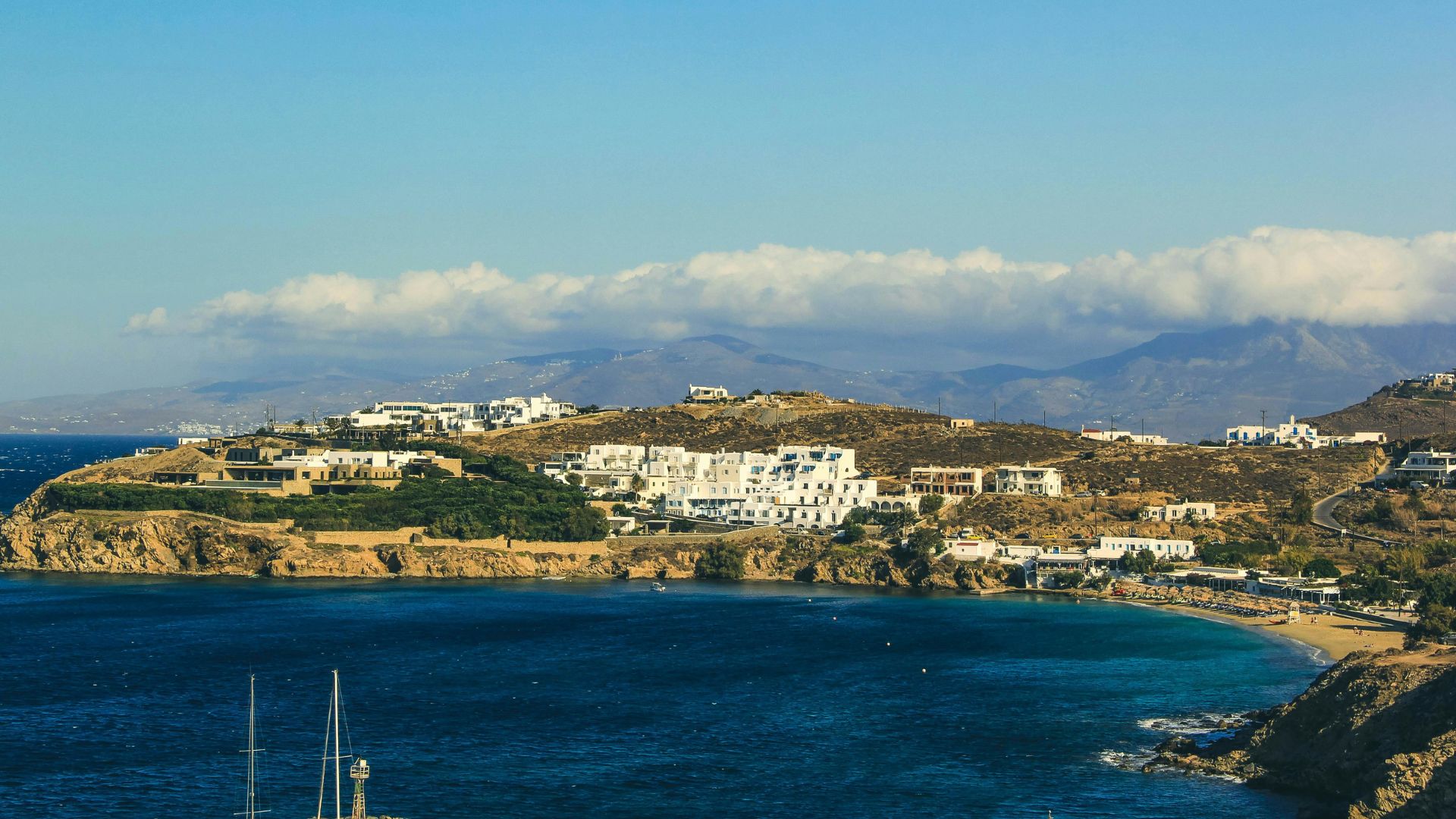 Aerial view of Mykonos, Greece, with white buildings, and blue waters.