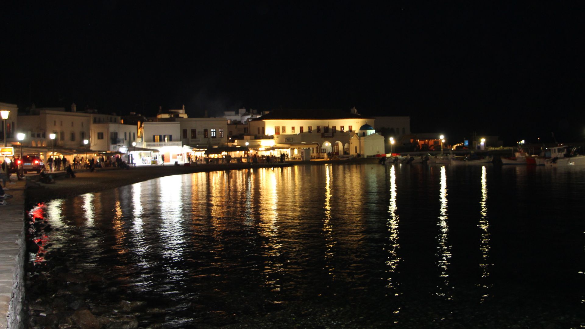 Night view of Mykonos waterfront with lights reflecting on the water.