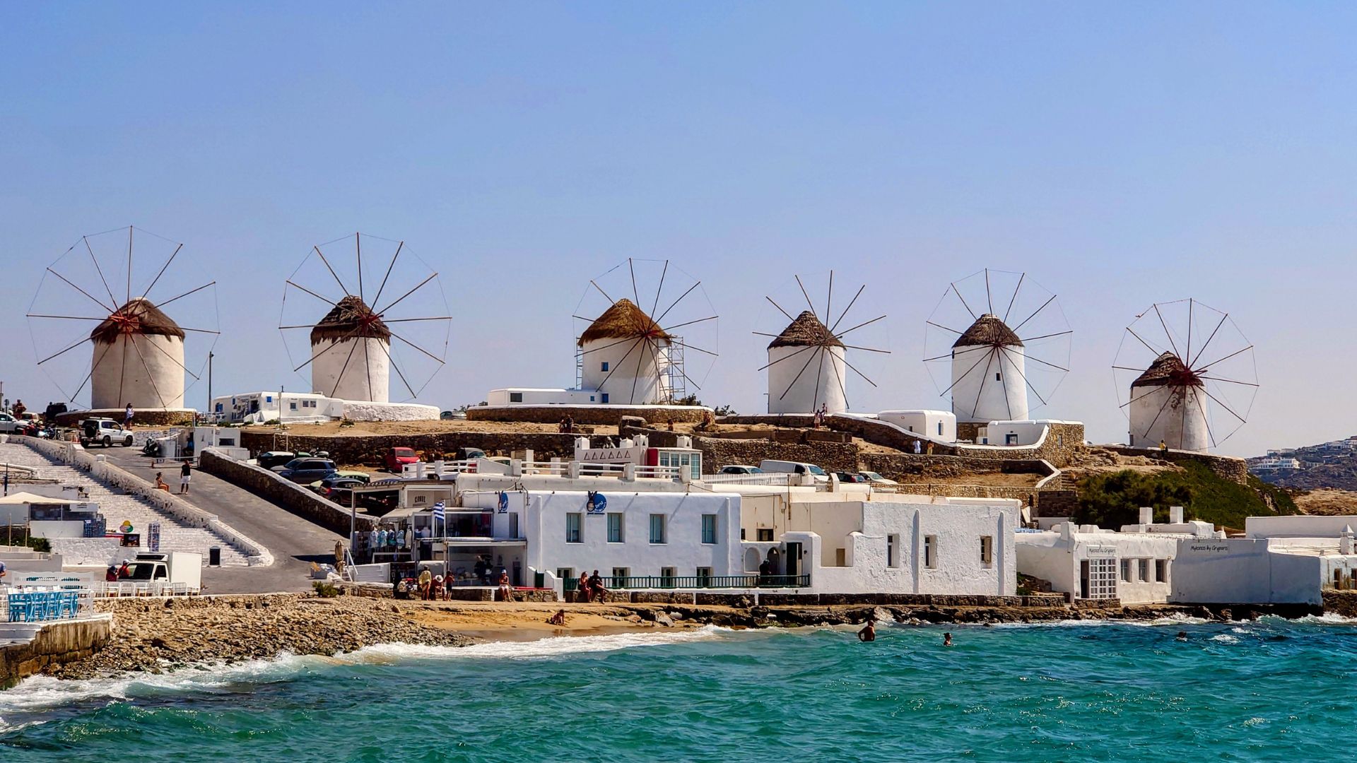 Mykonos windmills with white buildings and blue sea.