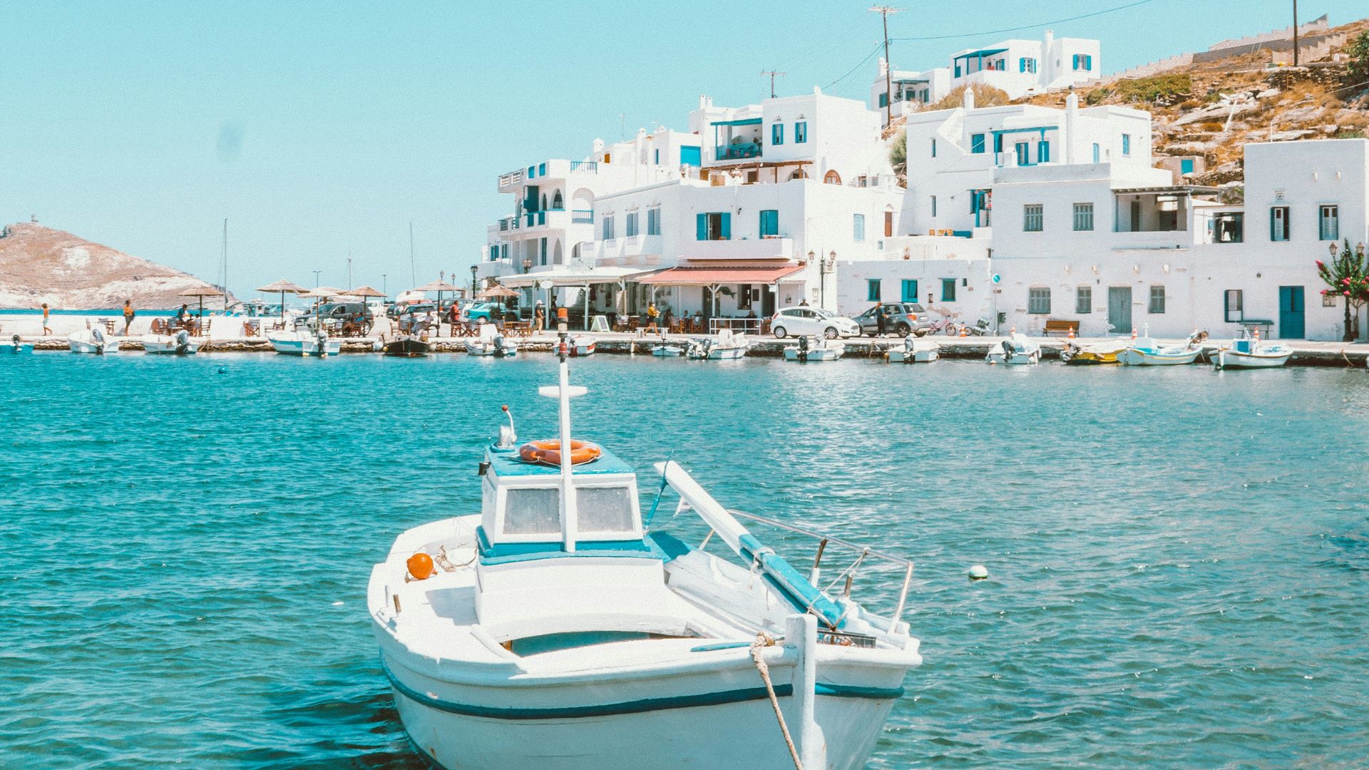 A boat in the water with a white village in the background.