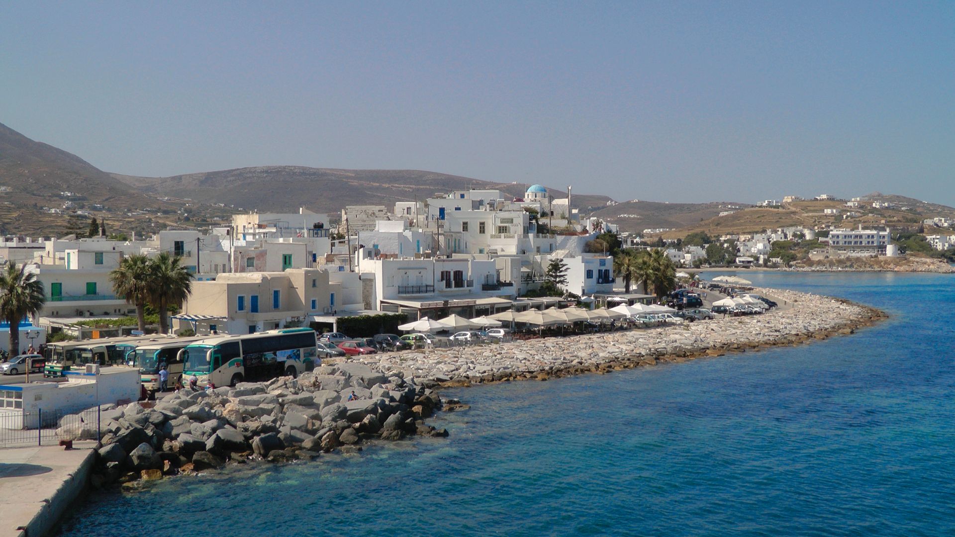 White buildings, blue water, rocky shores, and buses.