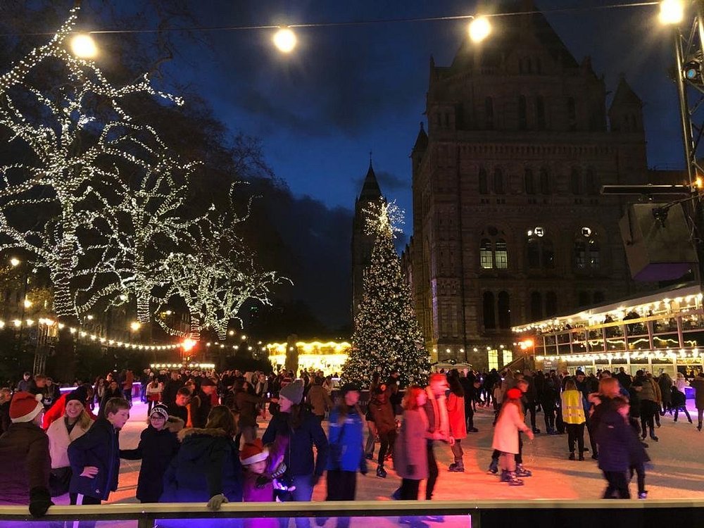 People skating at the Natural History Museum ice rink with a lit Christmas tree
