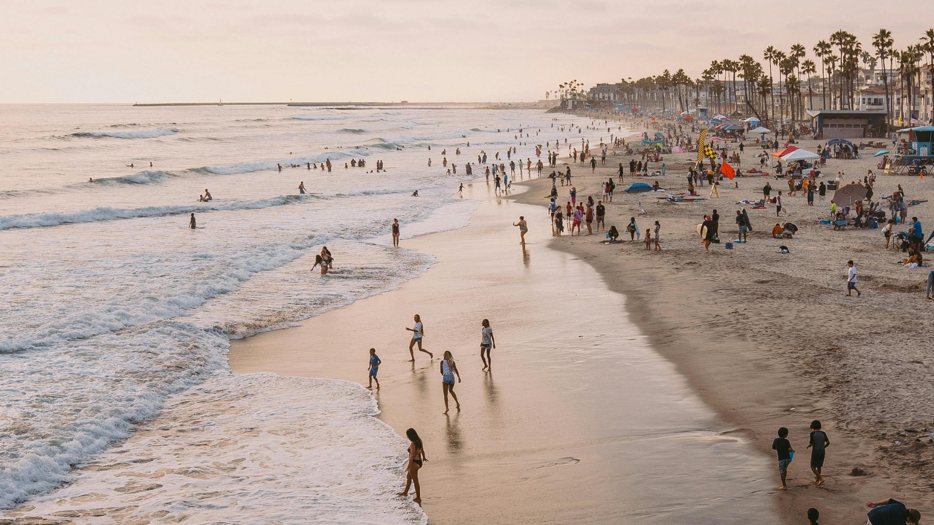  Aerial view of Oceanside Beach in San Diego County, California, with people enjoying the waves and shoreline during sunset