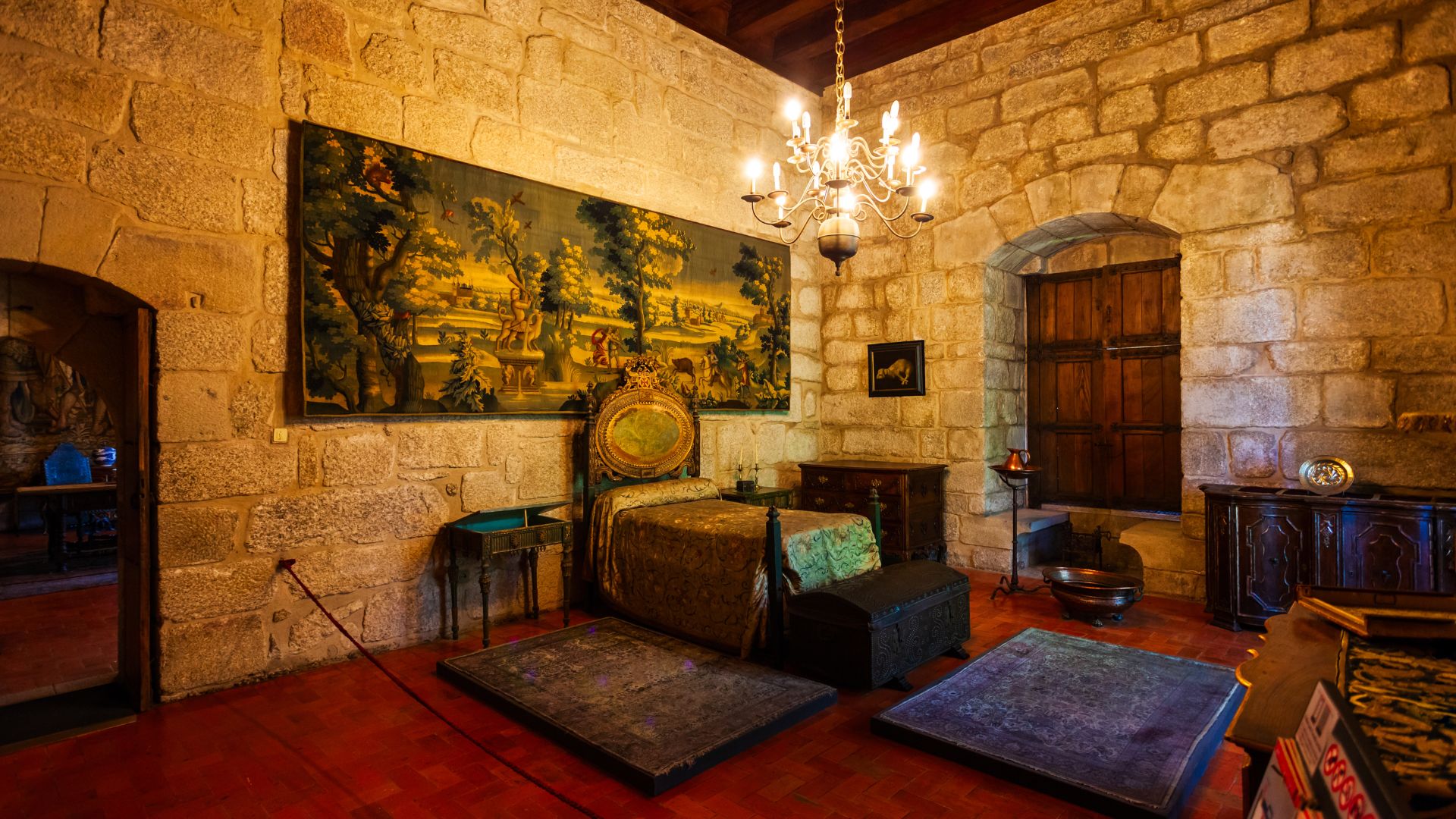 A richly decorated room with stone walls and a chandelier in the Palace of the Dukes of Braganza, Guimarães, Portugal.