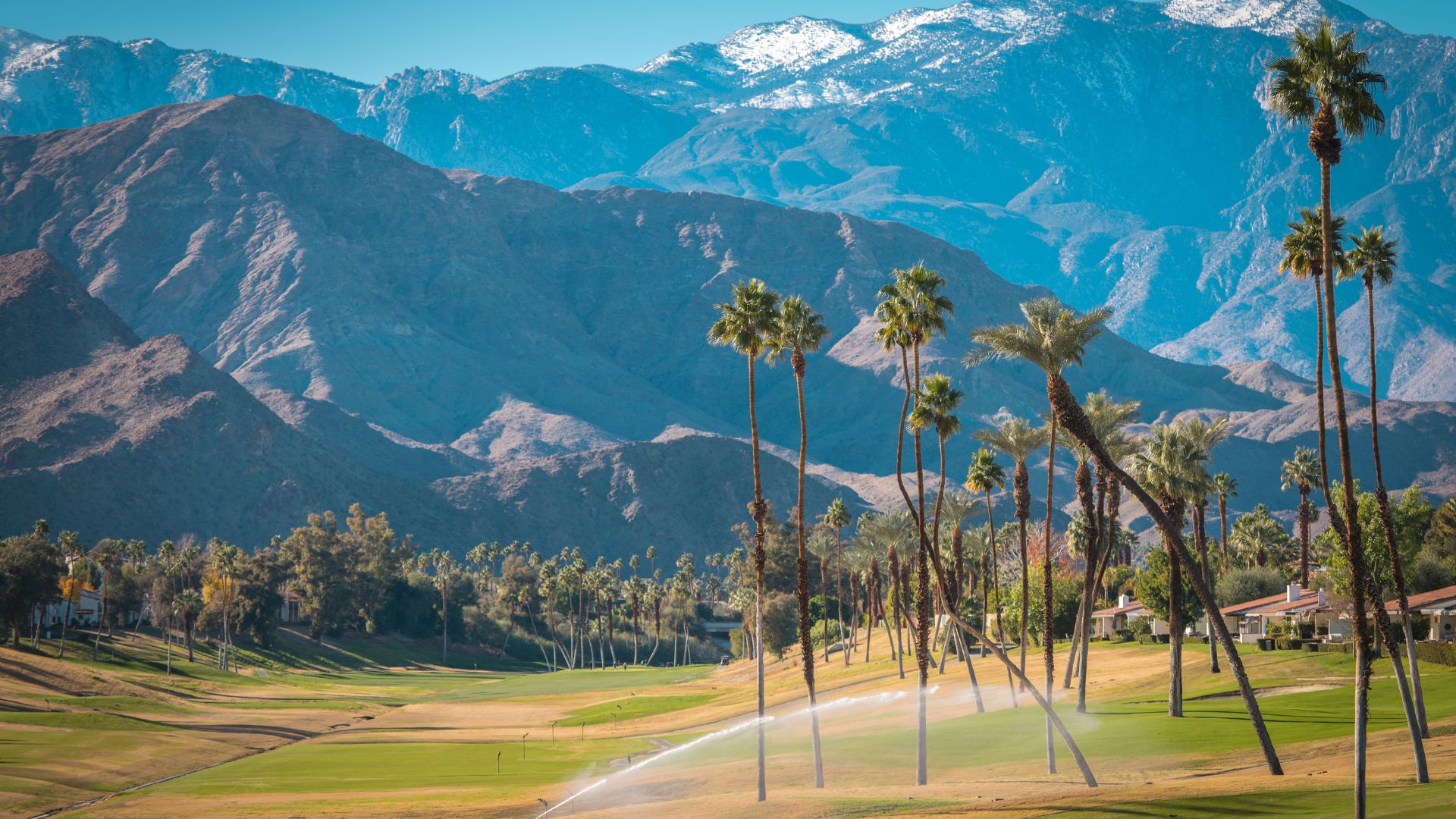 Scenic view of a golf course in Palm Desert, Southern California, featuring palm trees and the San Jacinto Mountains in the background.