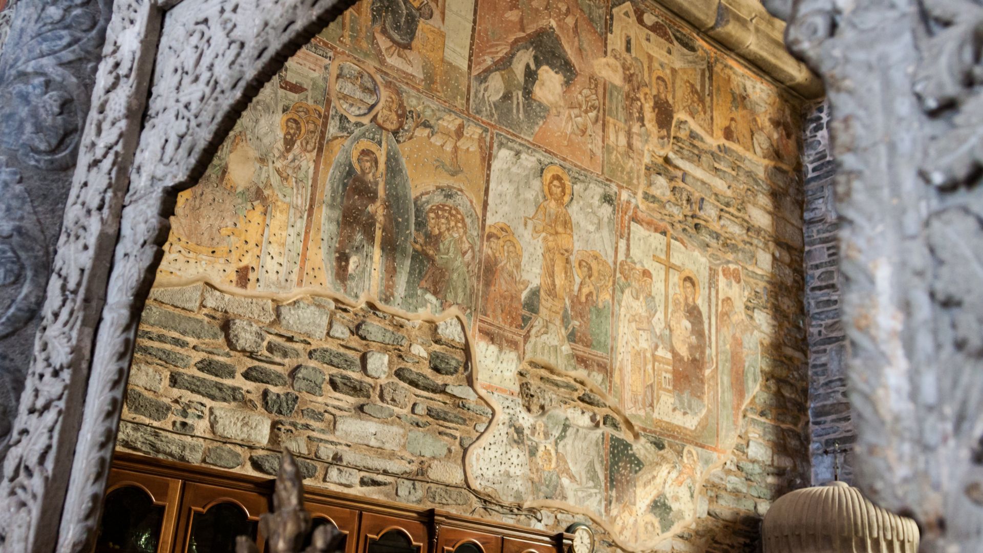 Interior view of Panagia Ekatontapiliani church in Paros, Greece, showing stone walls and religious frescoes.