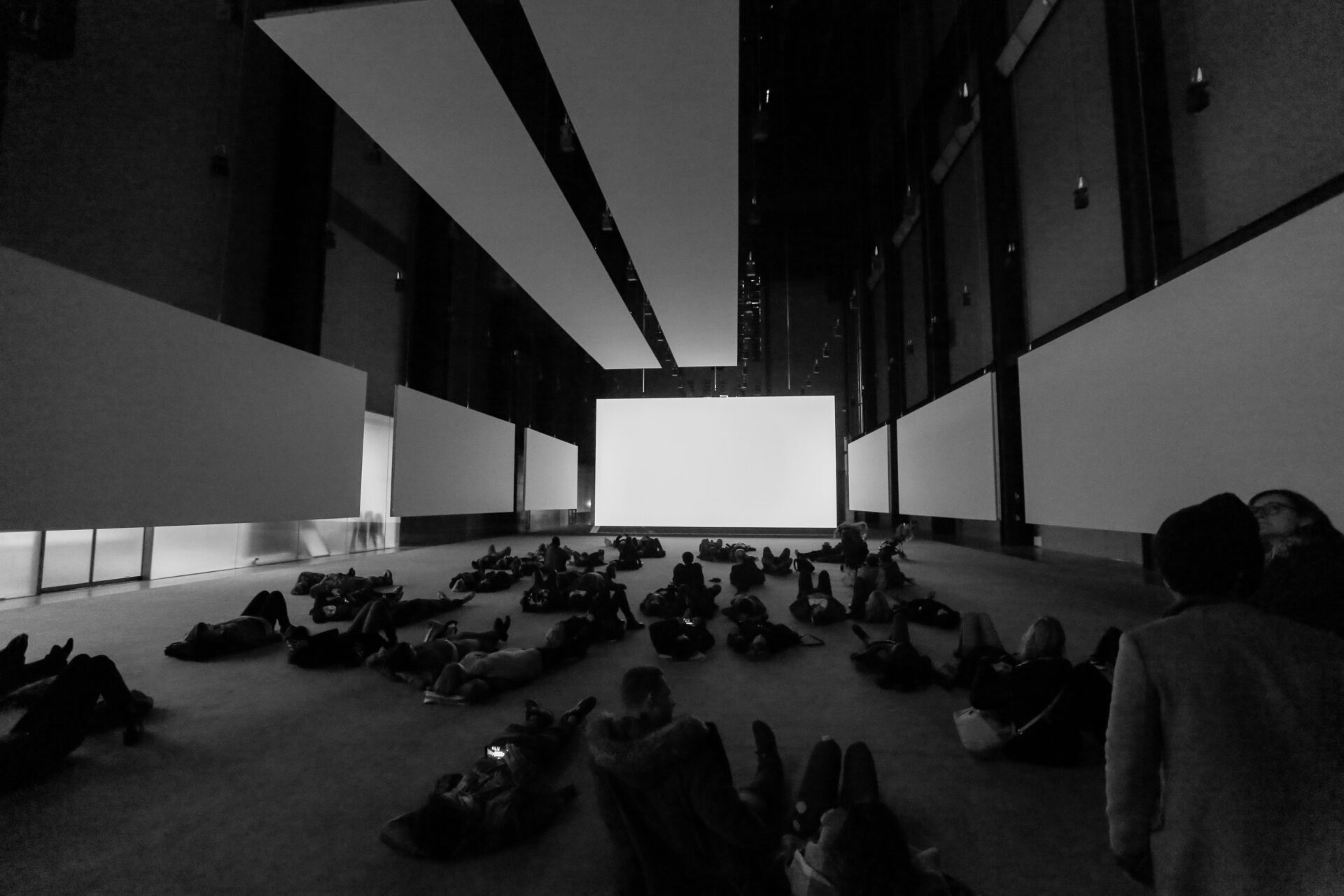 People lying on the floor inside Tate Modern's Turbine Hall, engaging with a large-scale installation in the spacious industrial interior
