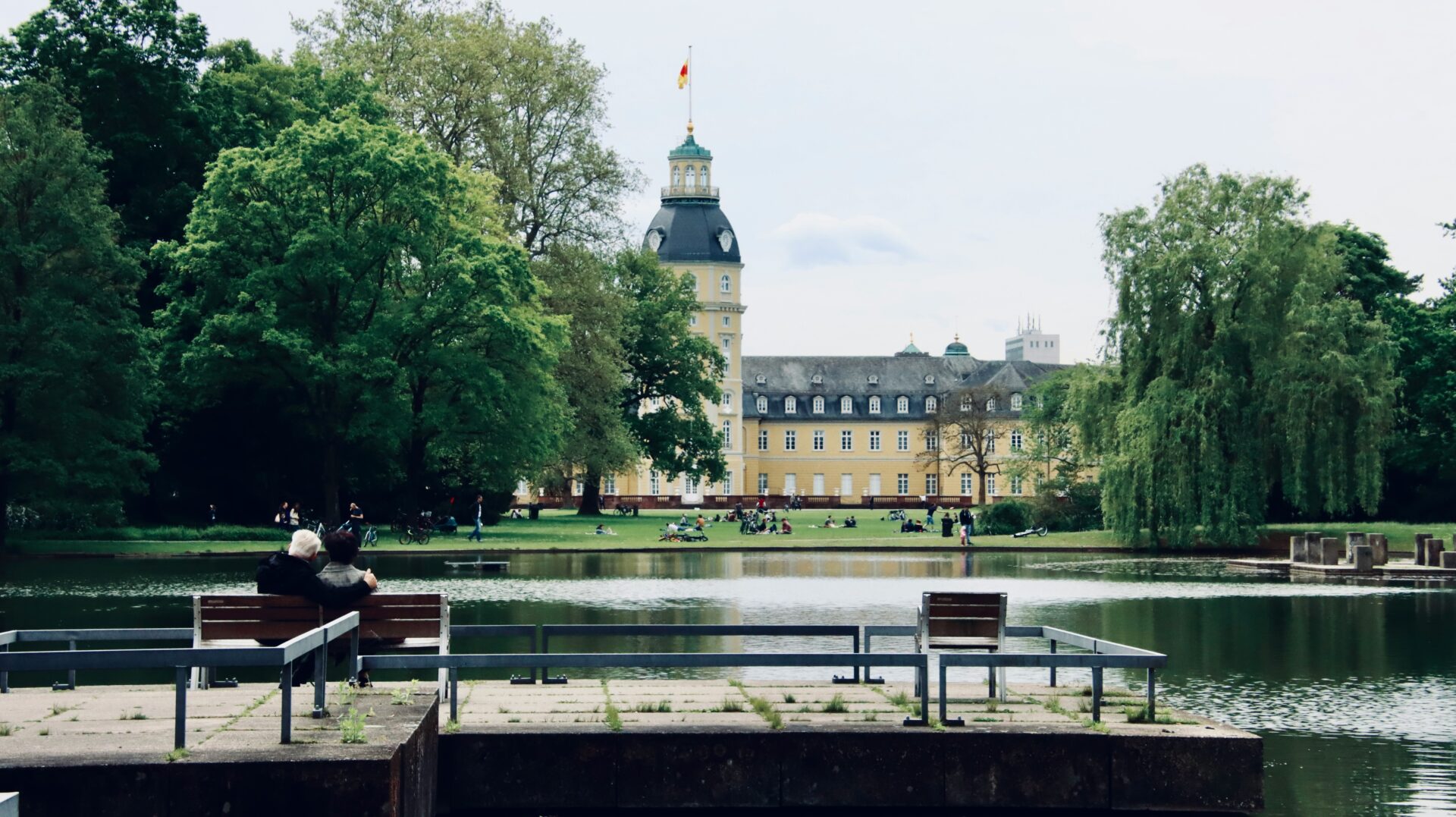 Tranquil scene of people resting by the water in Karlsruhe Palace park