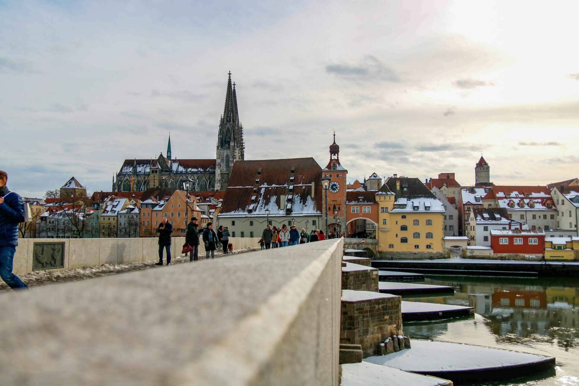 People walking across the historic Stone Bridge in Regensburg
