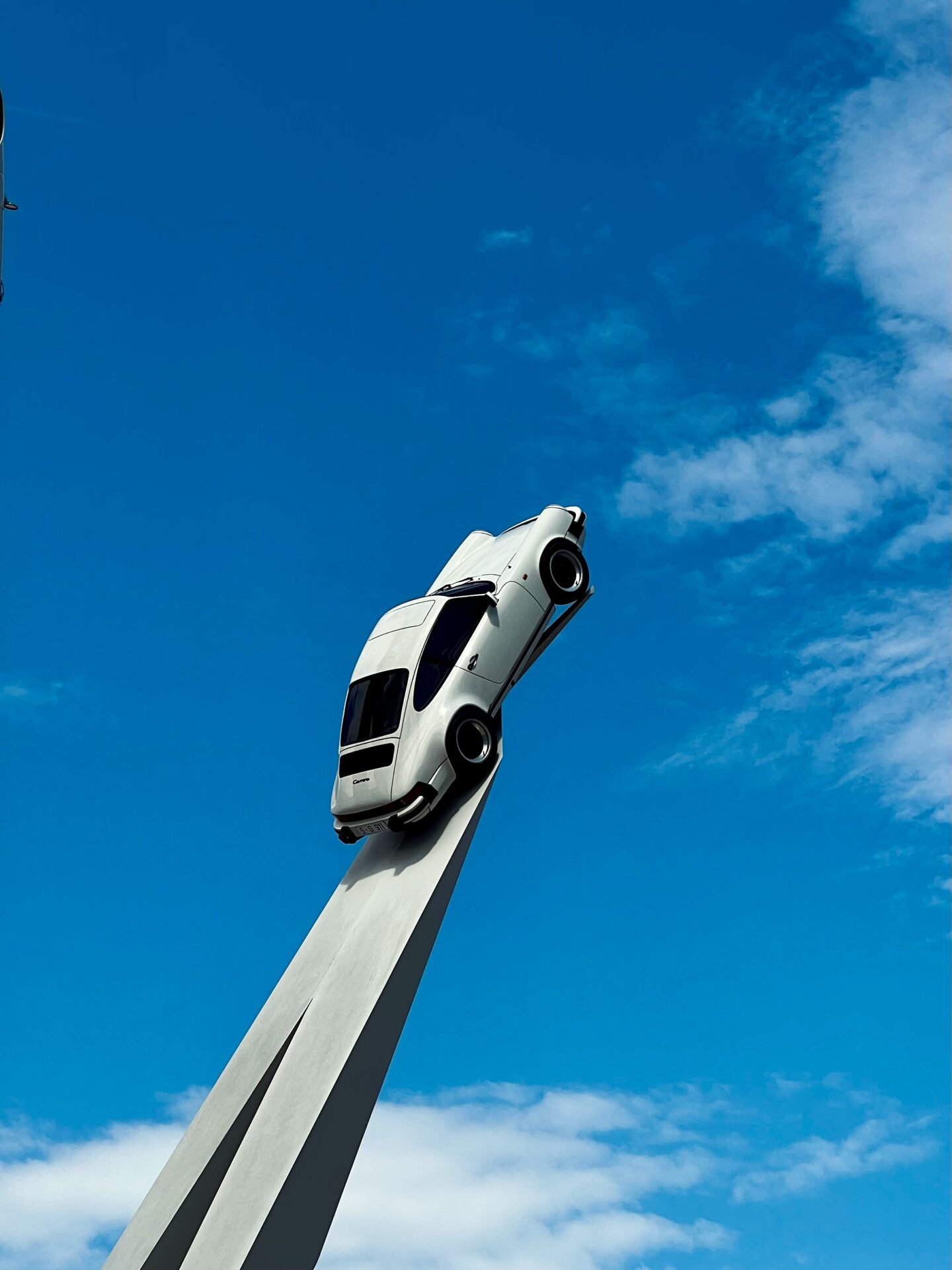 Exterior of the Porsche Museum in Stuttgart featuring the striking car sculpture with Porsche models mounted on tall white pillars.