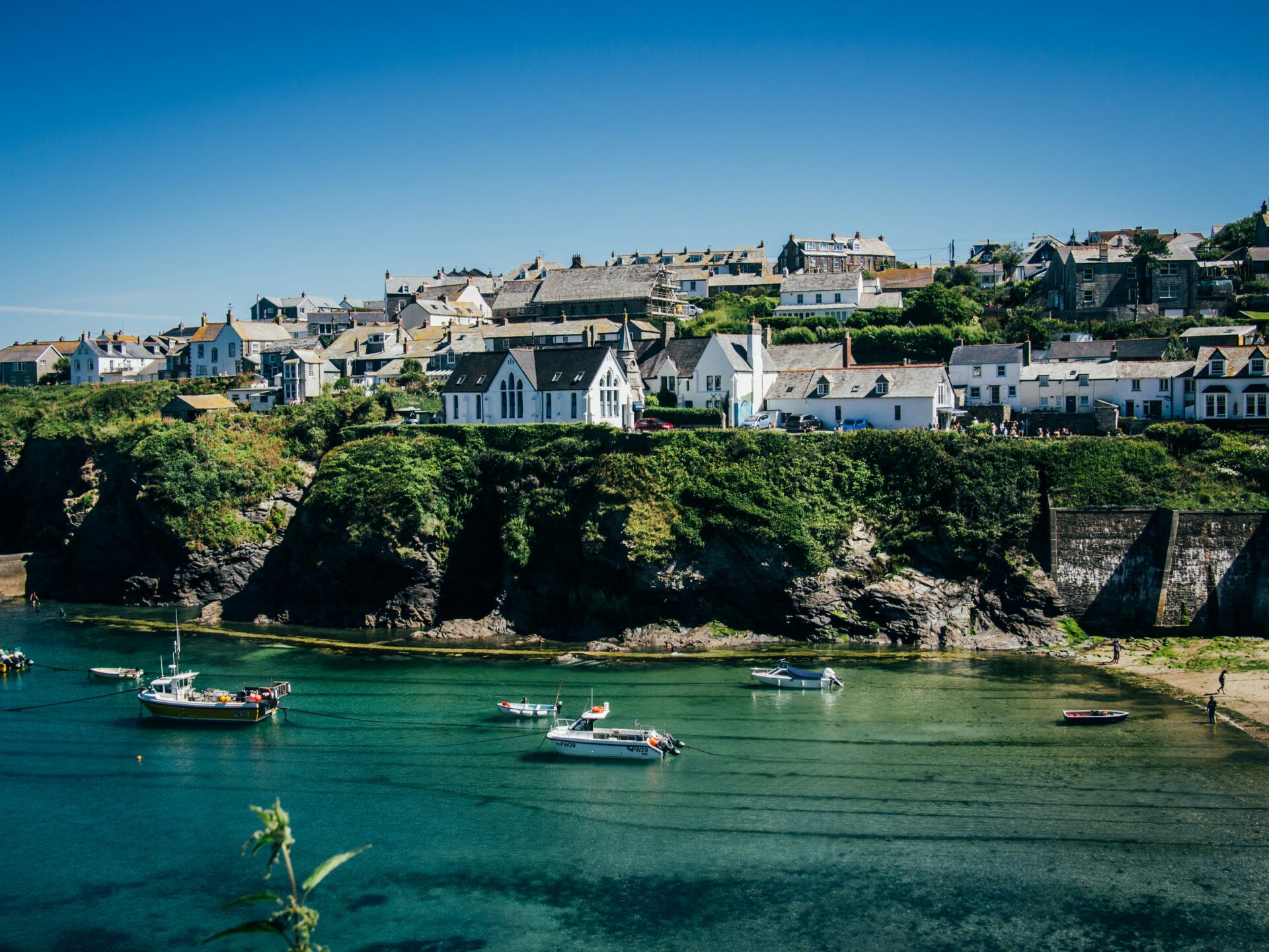 Scenic view of Port Isaac village, with the sparkling sea and boats moored in the harbour.