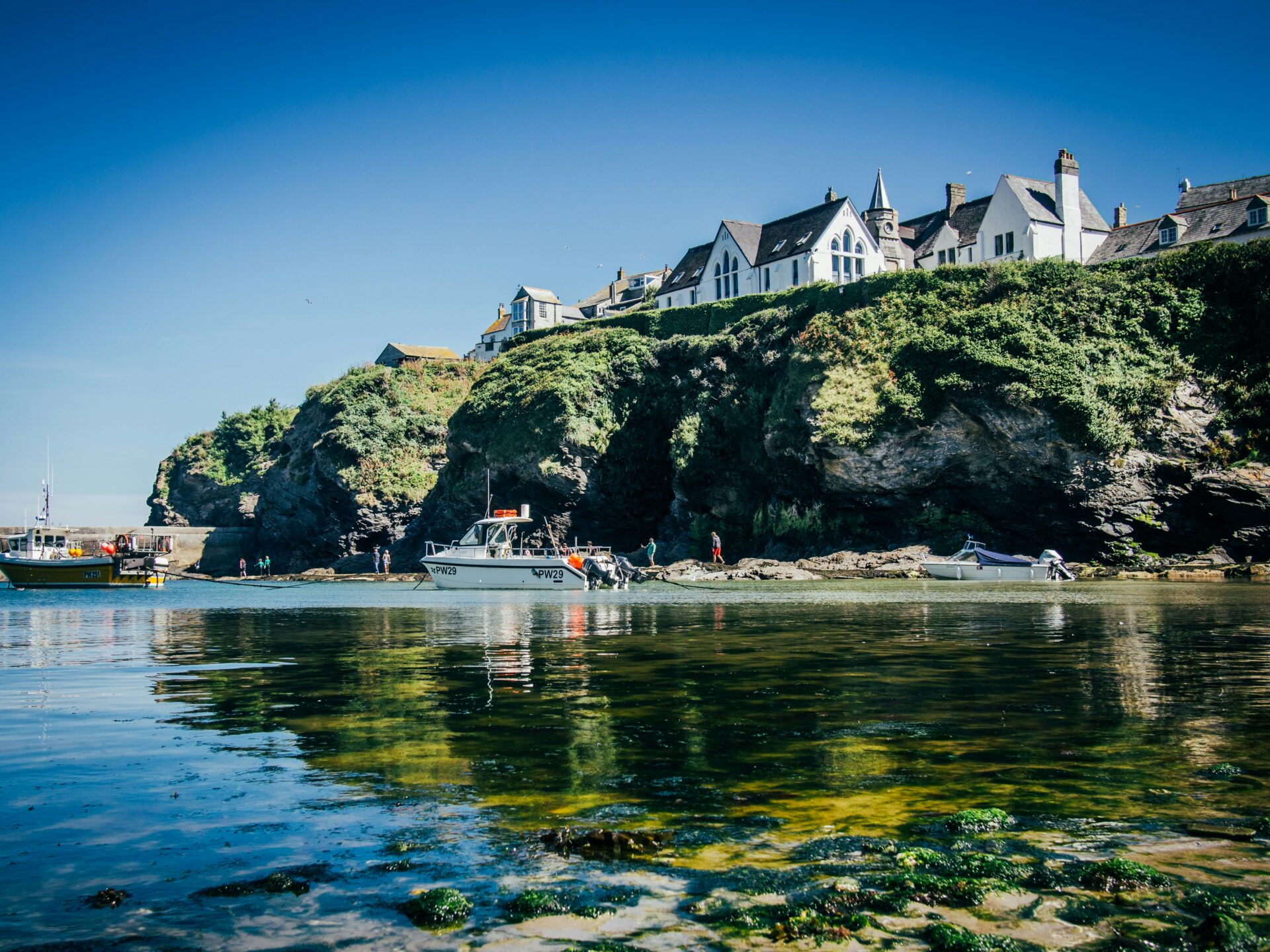 Port Isaac village with its whitewashed houses overlooking the calm waters of the harbour.