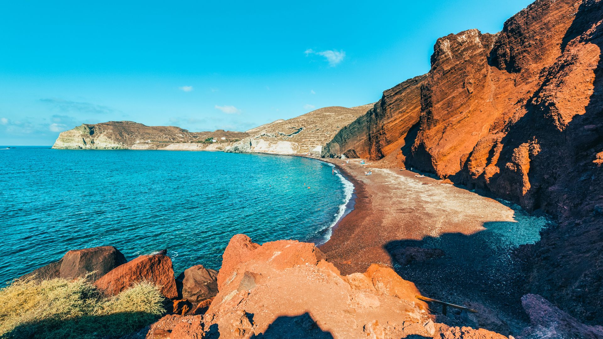 The rocky Red Beach in Santorini, Greece with red cliffs and blue water.