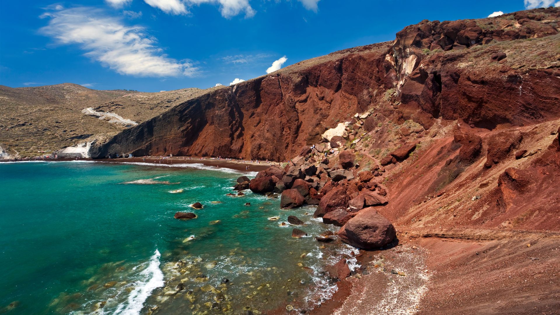 The rocky Red Beach in Santorini, Greece with red cliffs and blue water.