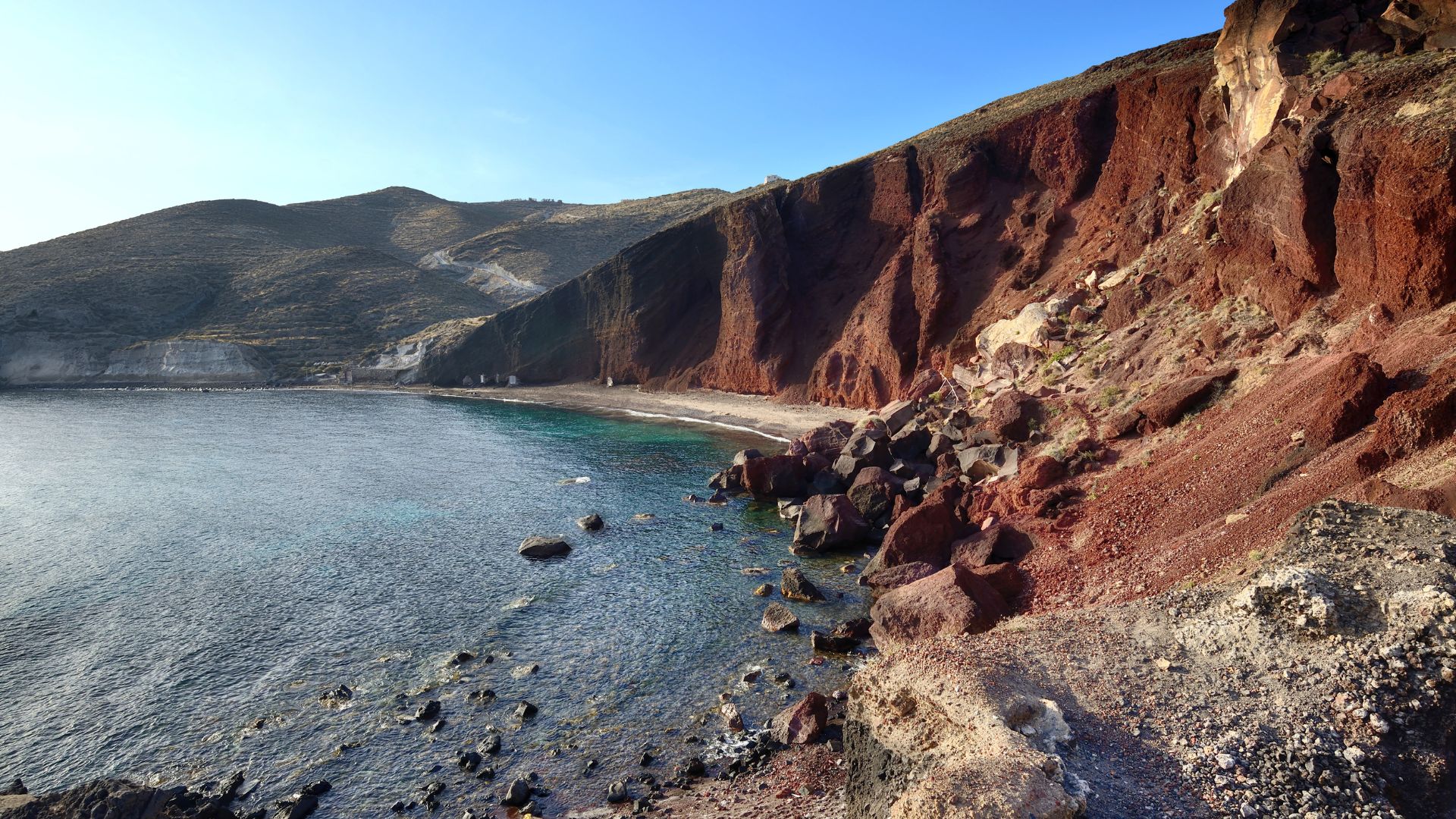 The rocky Red Beach in Santorini, Greece with red cliffs and blue water.