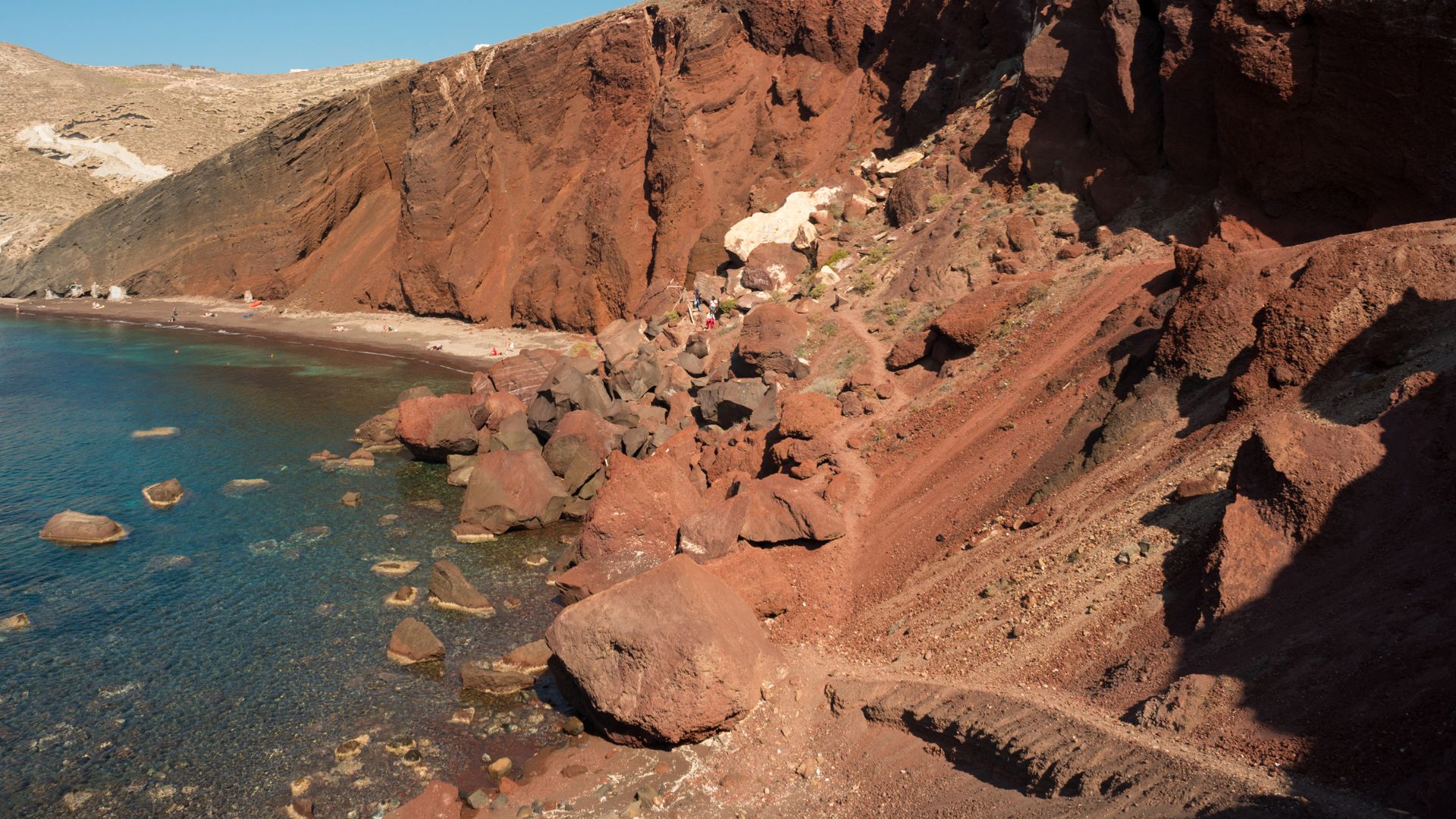 The rocky Red Beach in Santorini, Greece with red cliffs and blue water.