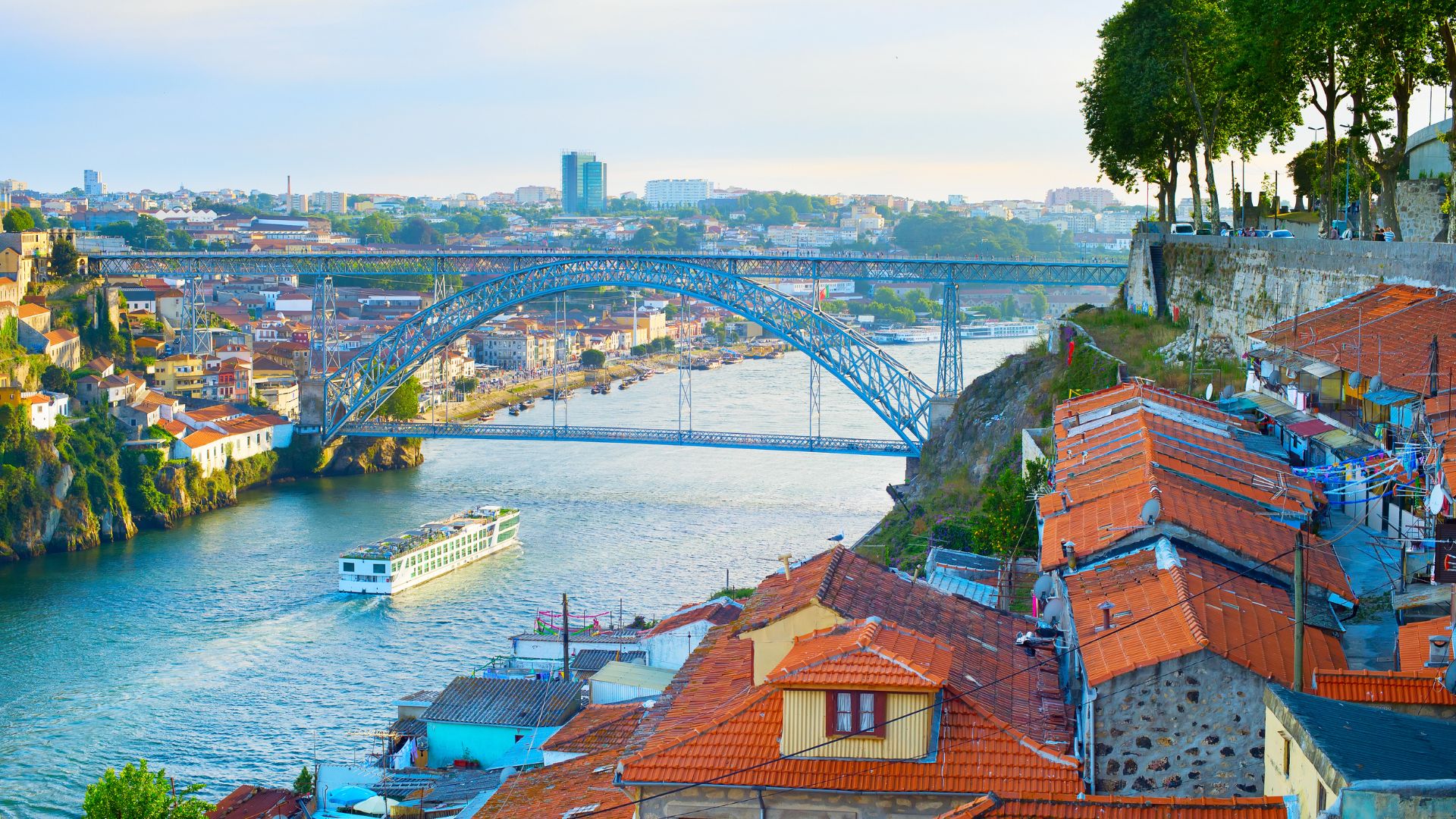 Scenic view of the Douro River in Portugal with the Dom Luís I Bridge in the background, showcasing a river cruise ship and the colorful architecture of Porto. This image captures the beauty of the Douro Valley, a popular destination for river cruises and wine lovers.